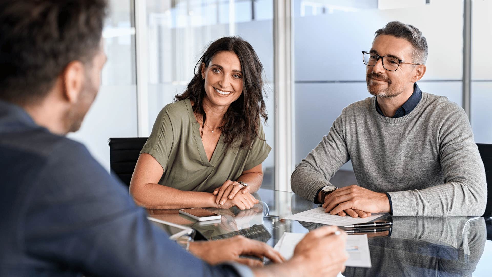 man and woman listening to other man while smiling 