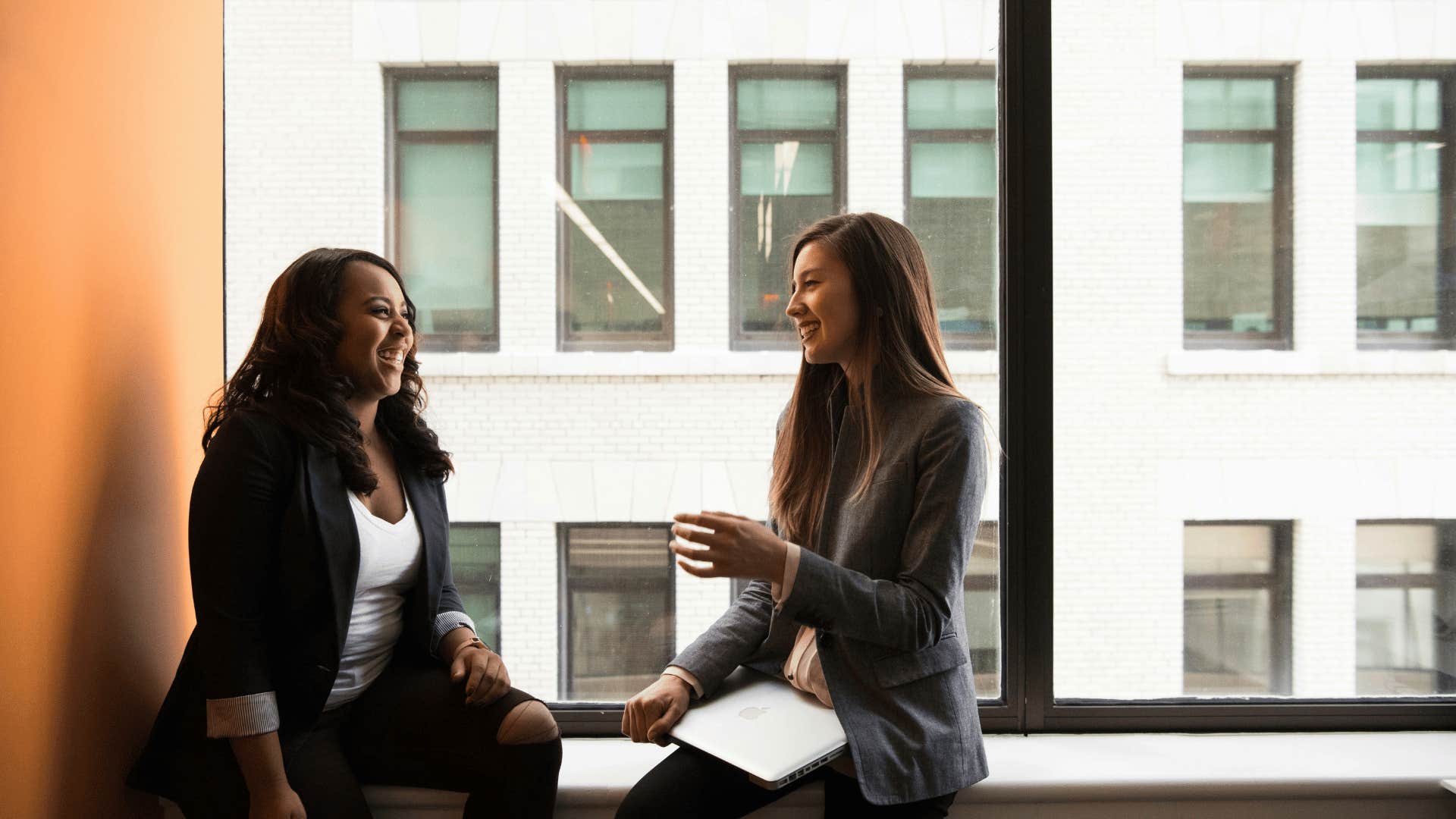 women sitting next to window and talking