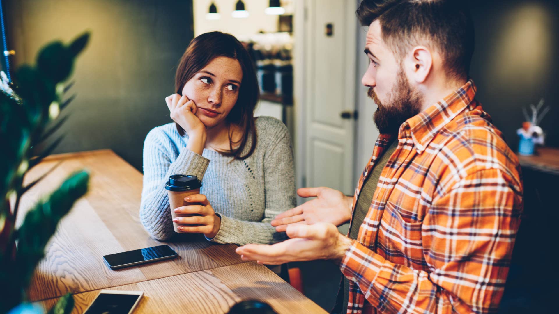 Man looking defensive and confused in front of his upset wife.