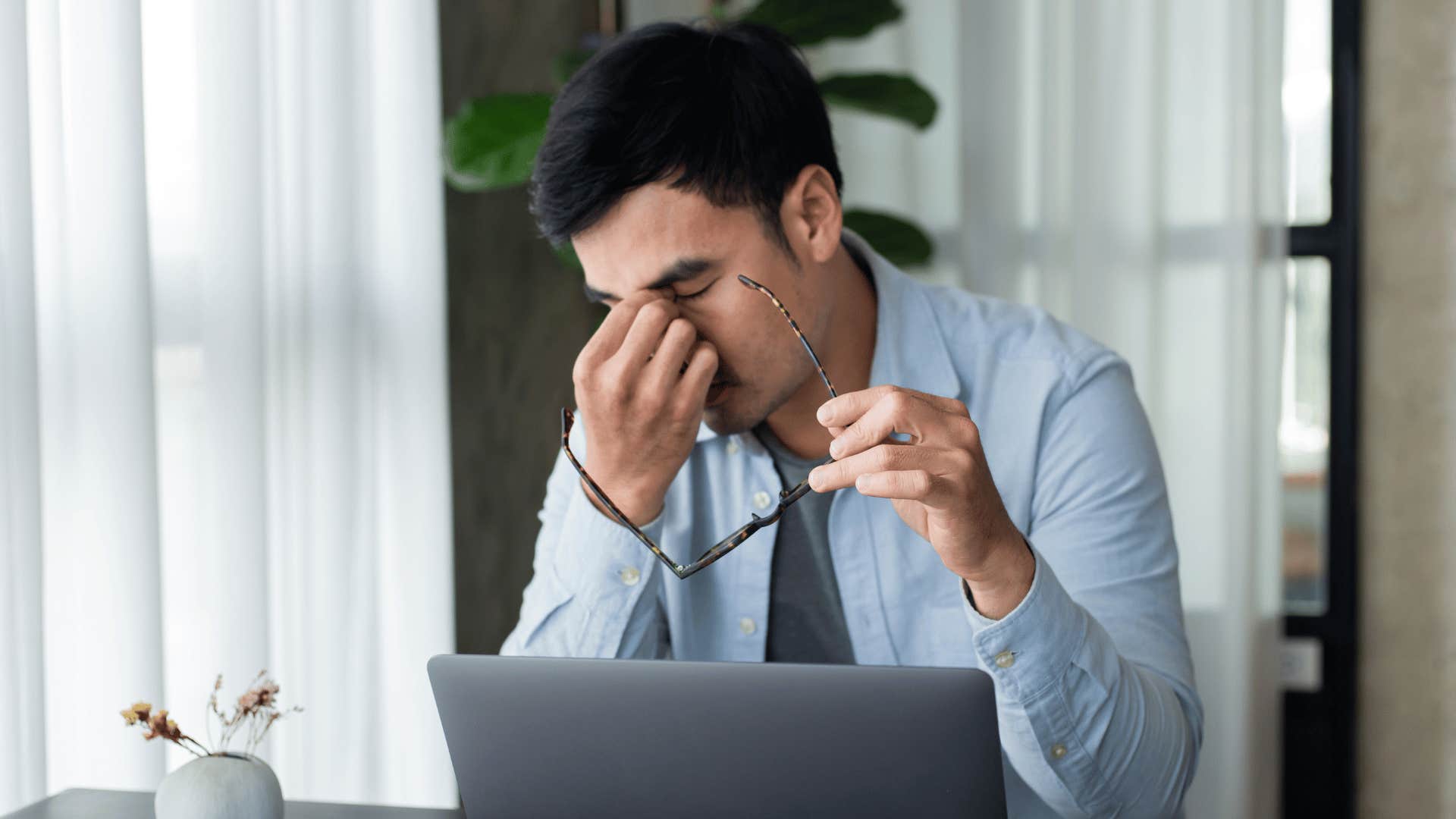 man looking tired while working on laptop