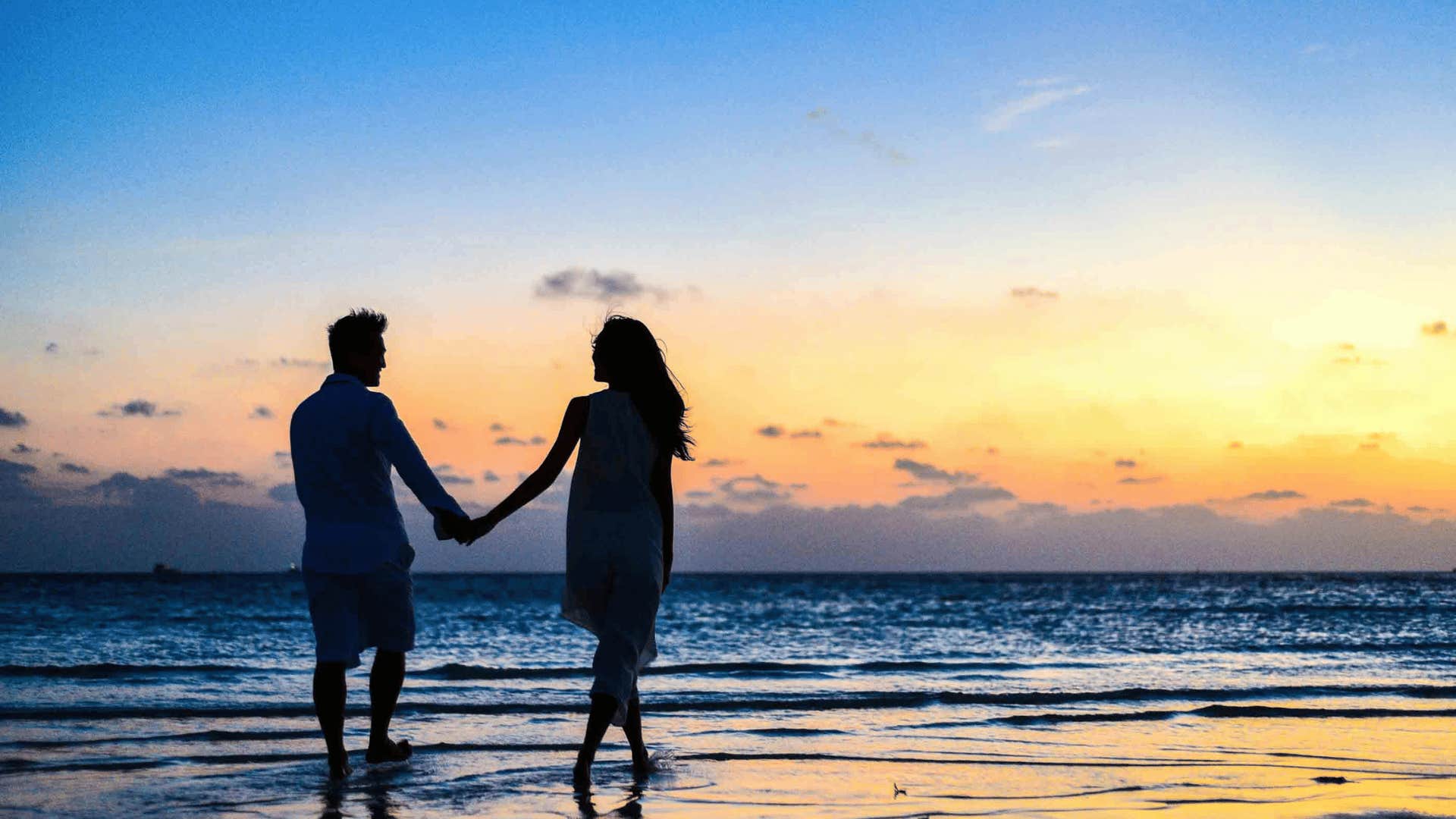 couple holding hands walking on the beach