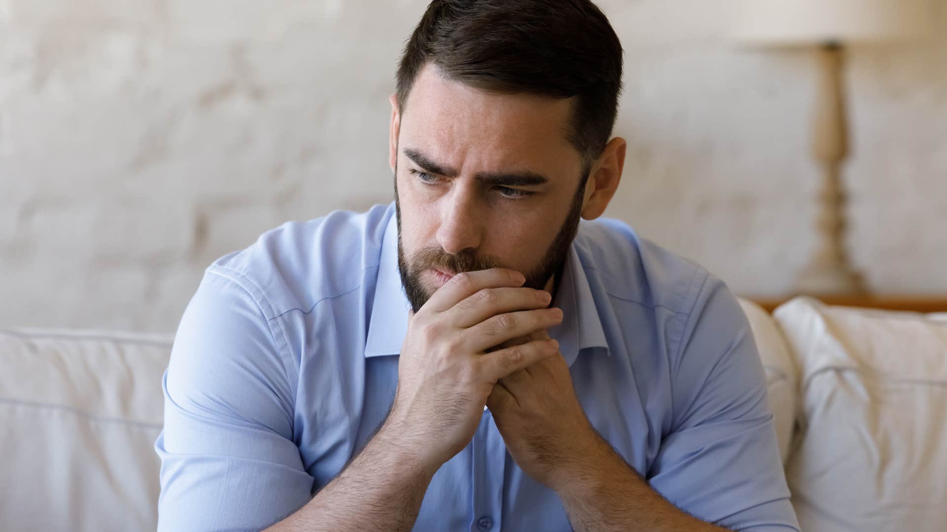 Adult man looking upset with his head in his hands