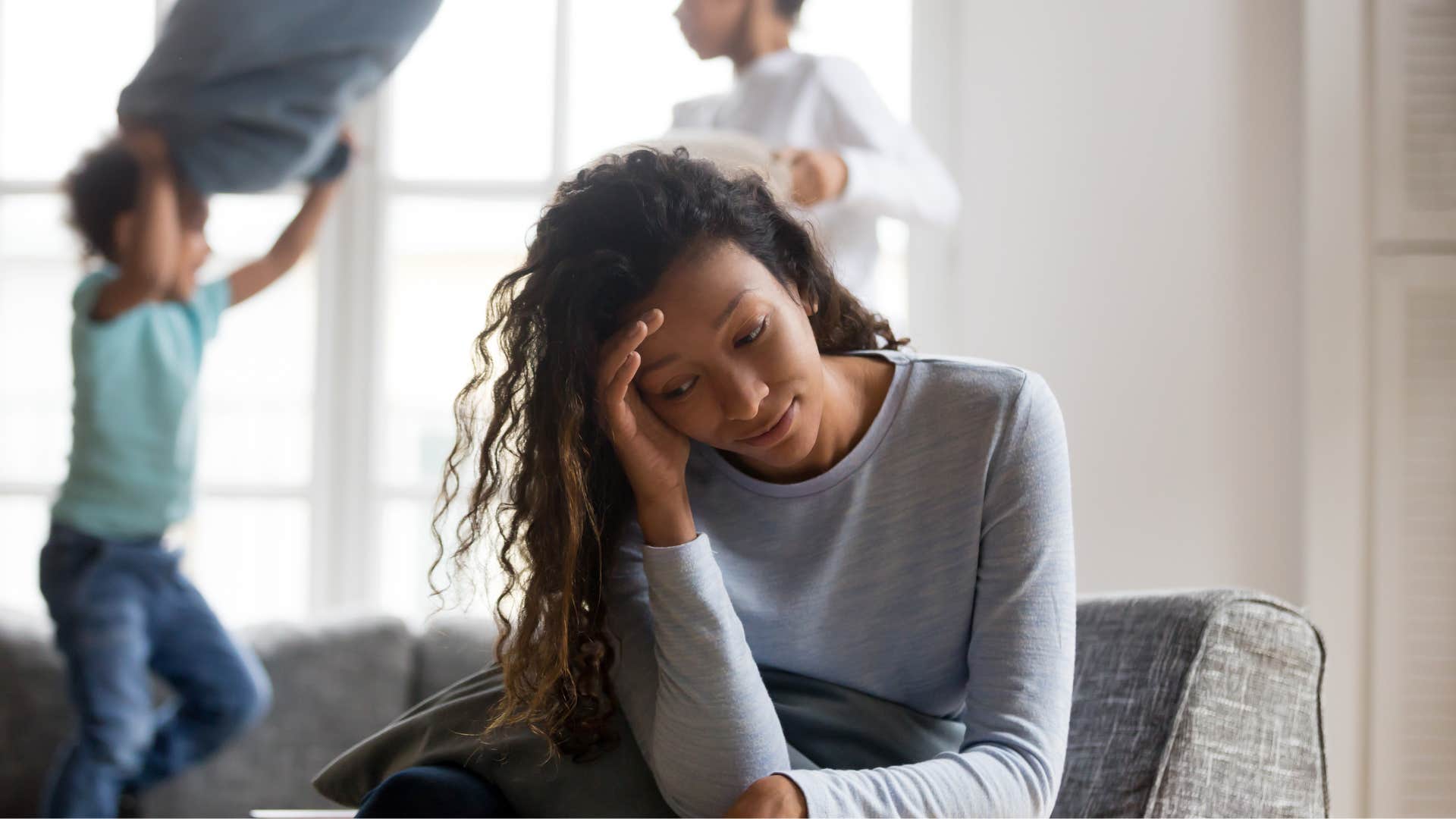 Woman looking annoyed while her kids play behind her