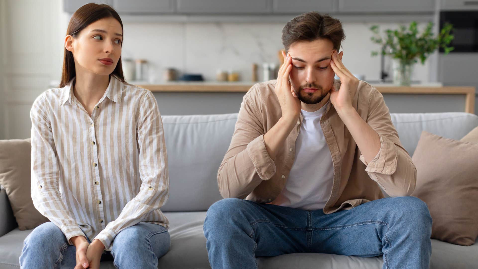 Man looking upset sitting next to his girlfriend.