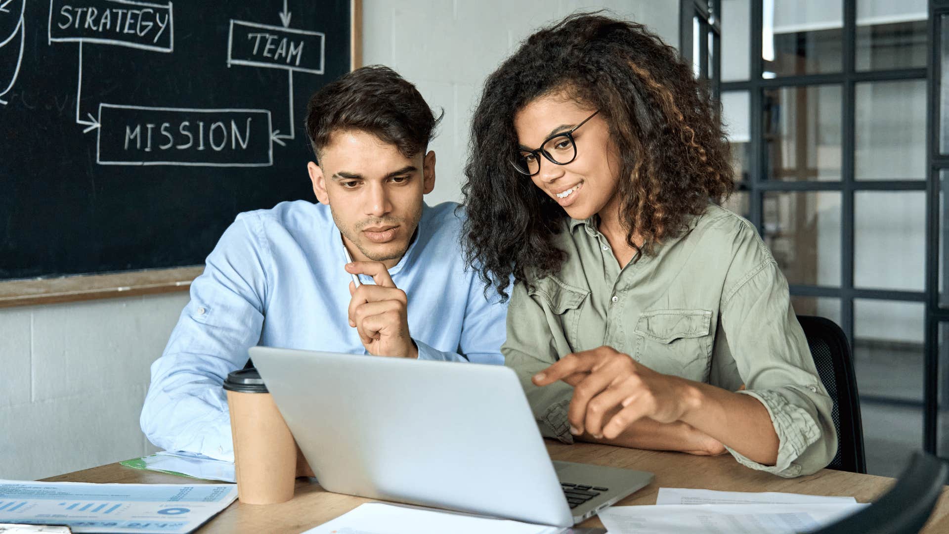 woman showing man something on laptop