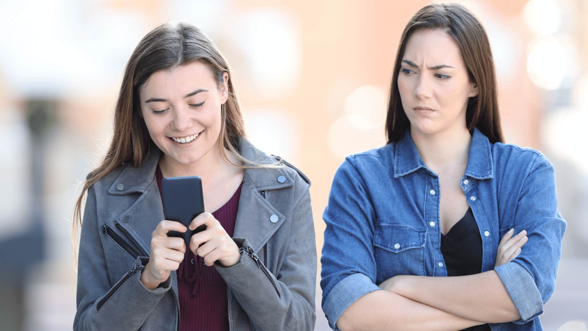 happy woman looking at phone while another woman looks at her