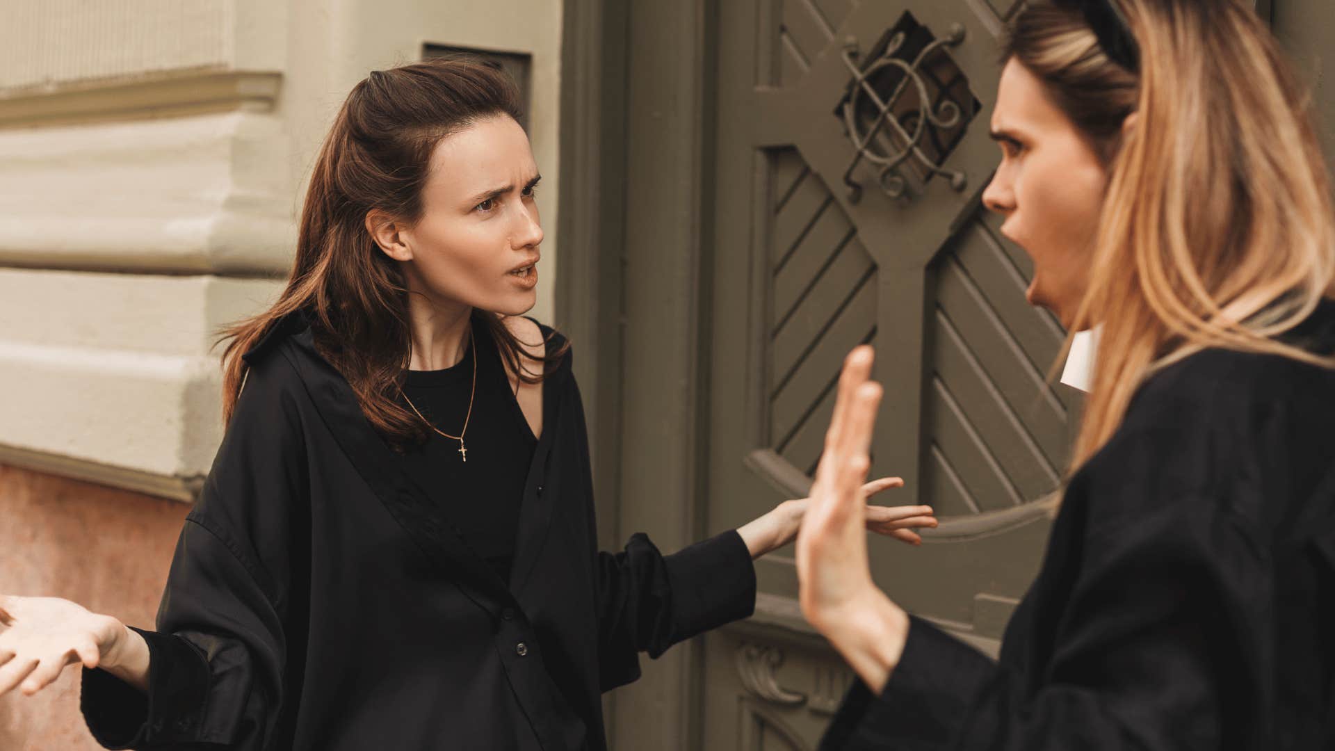 two women arguing outside of building