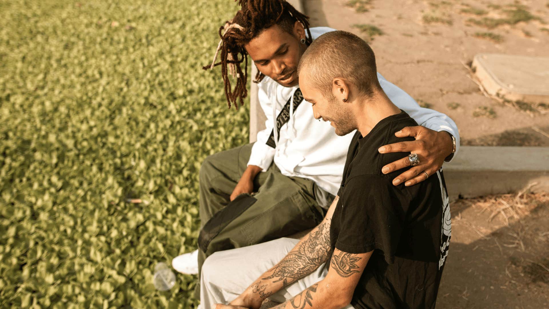 two men sitting next to the sand talking to each other