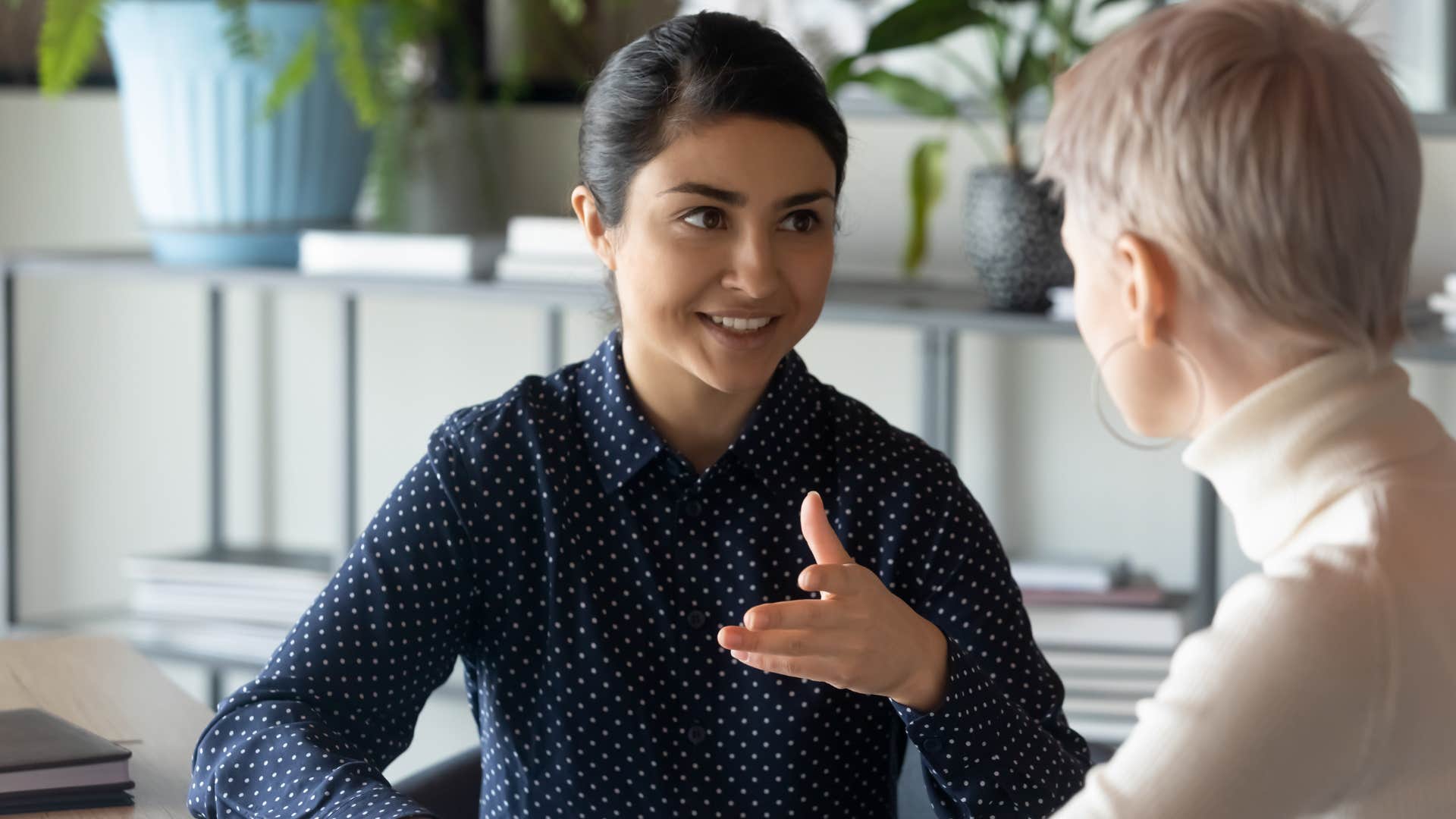 Woman smiling and talking to a peer at work.