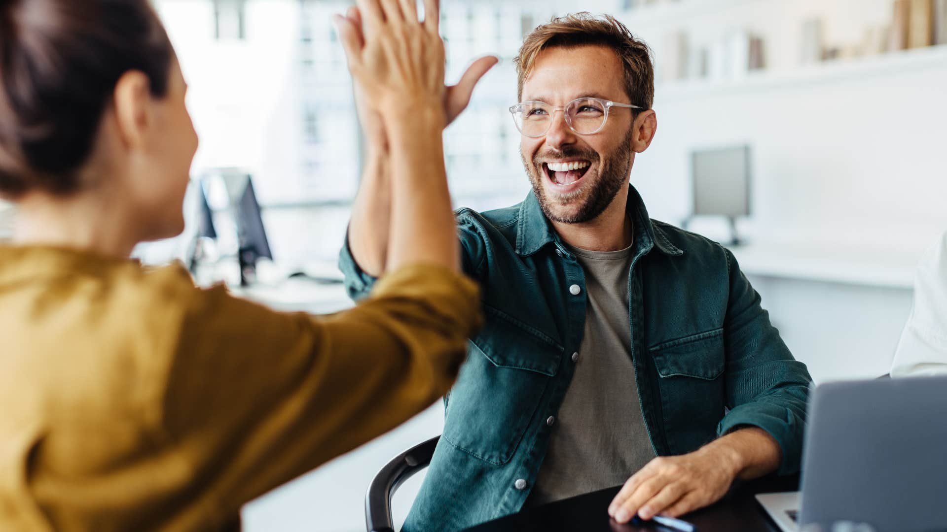 Man smiling and high-fiving a woman.