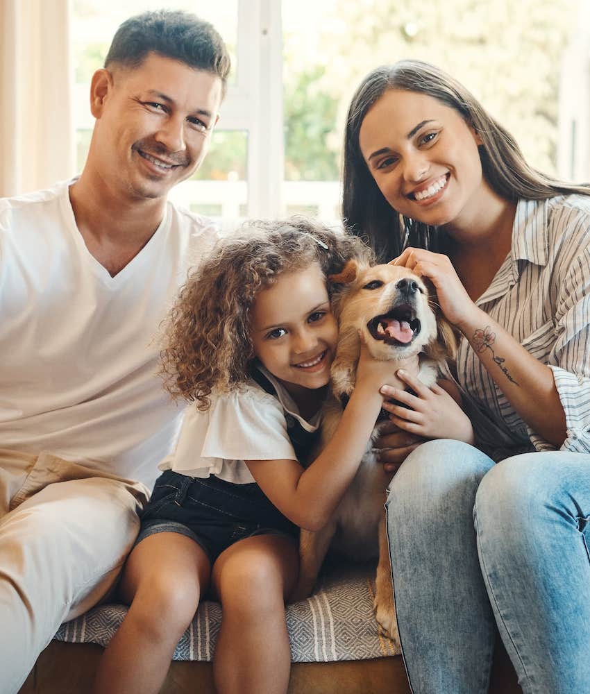 Man and woman sit on couch with child and dog