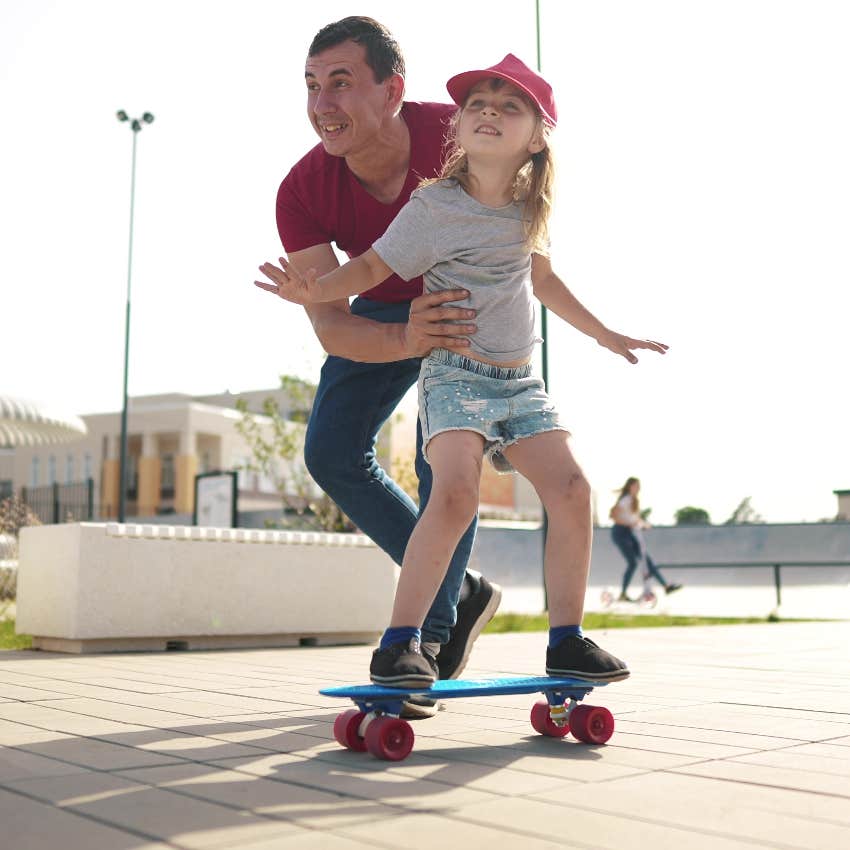 Supportive parent helping their kid skateboard