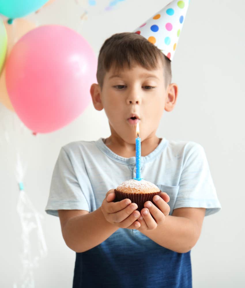 little boy blowing out birthday candle on cupcake