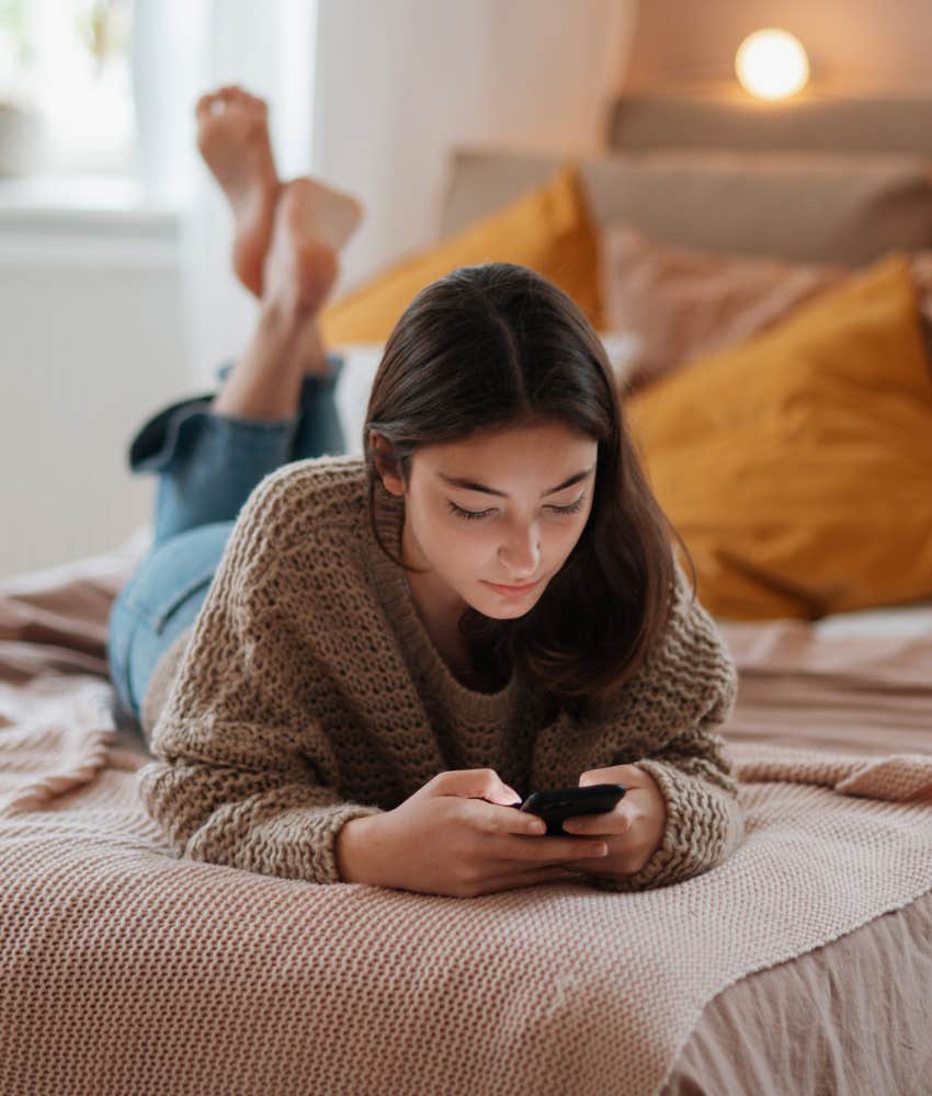 teenage girl scrolling phone in her bedroom