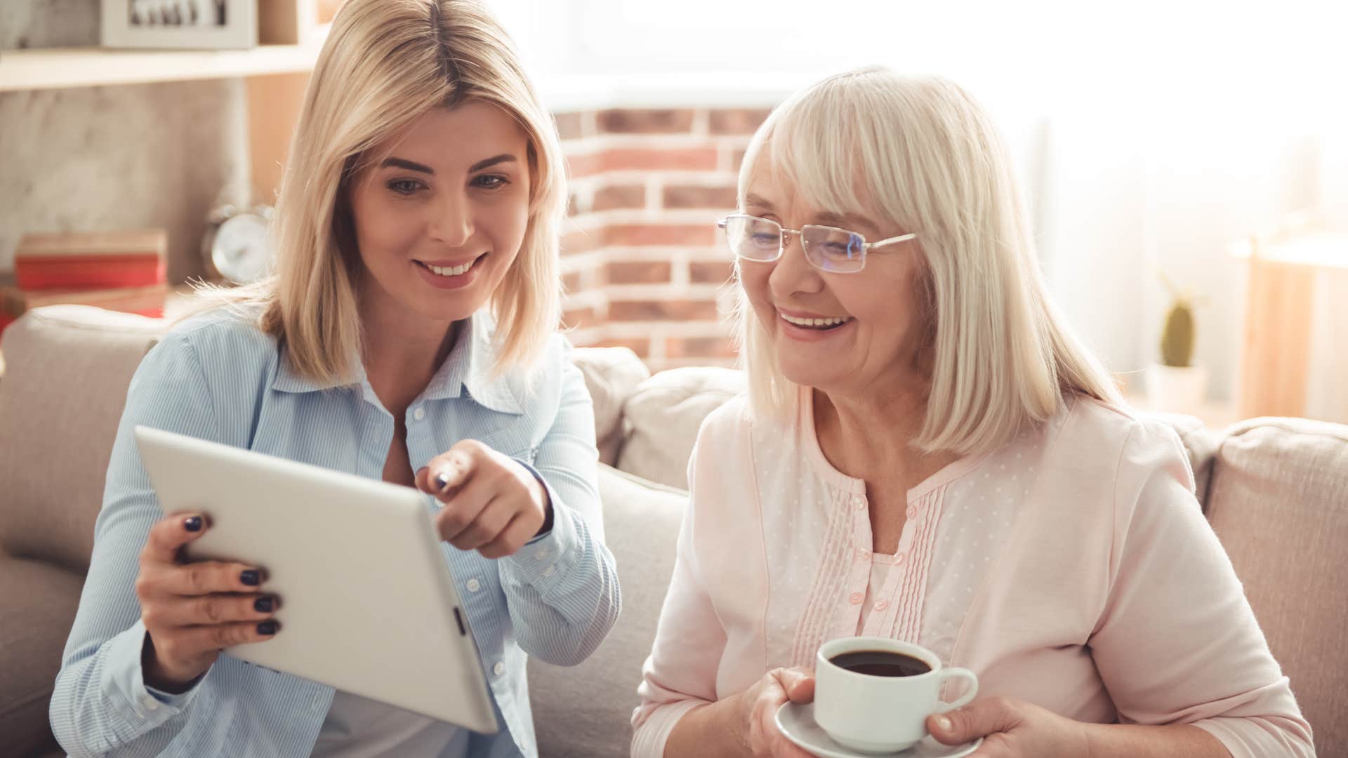 Smiling woman showing her older mother something on a tablet.