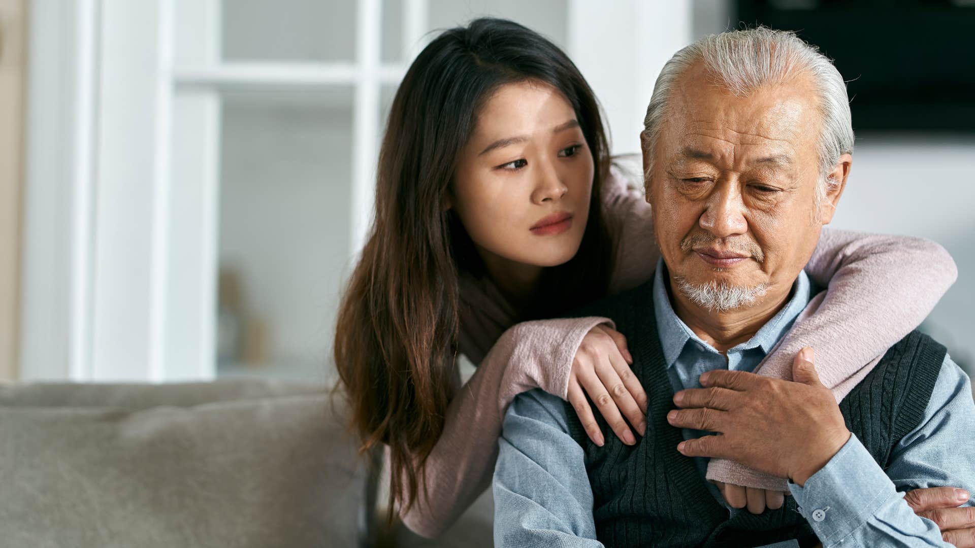 Woman comforting her upset older father.