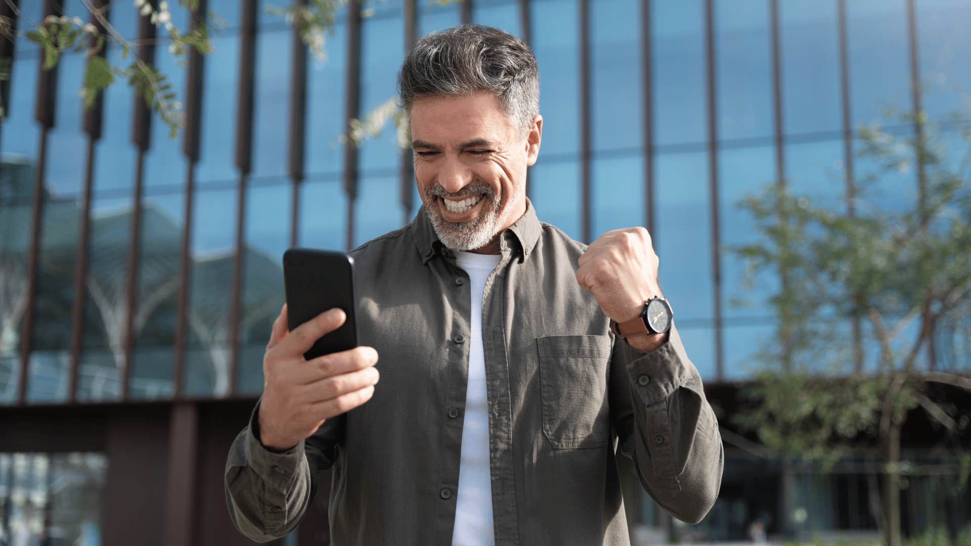 older man smiling at phone seeming excited