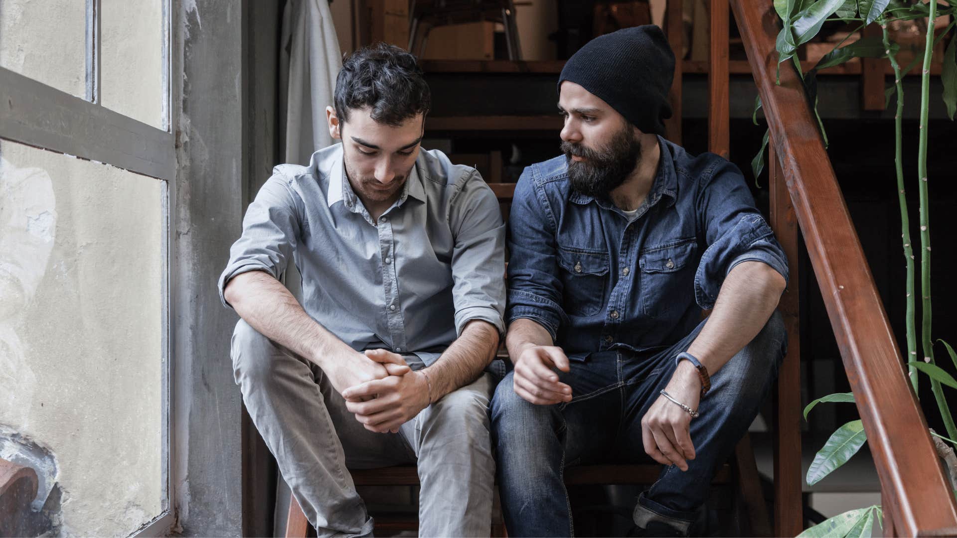 two men sitting on the stairs while one man looks upset