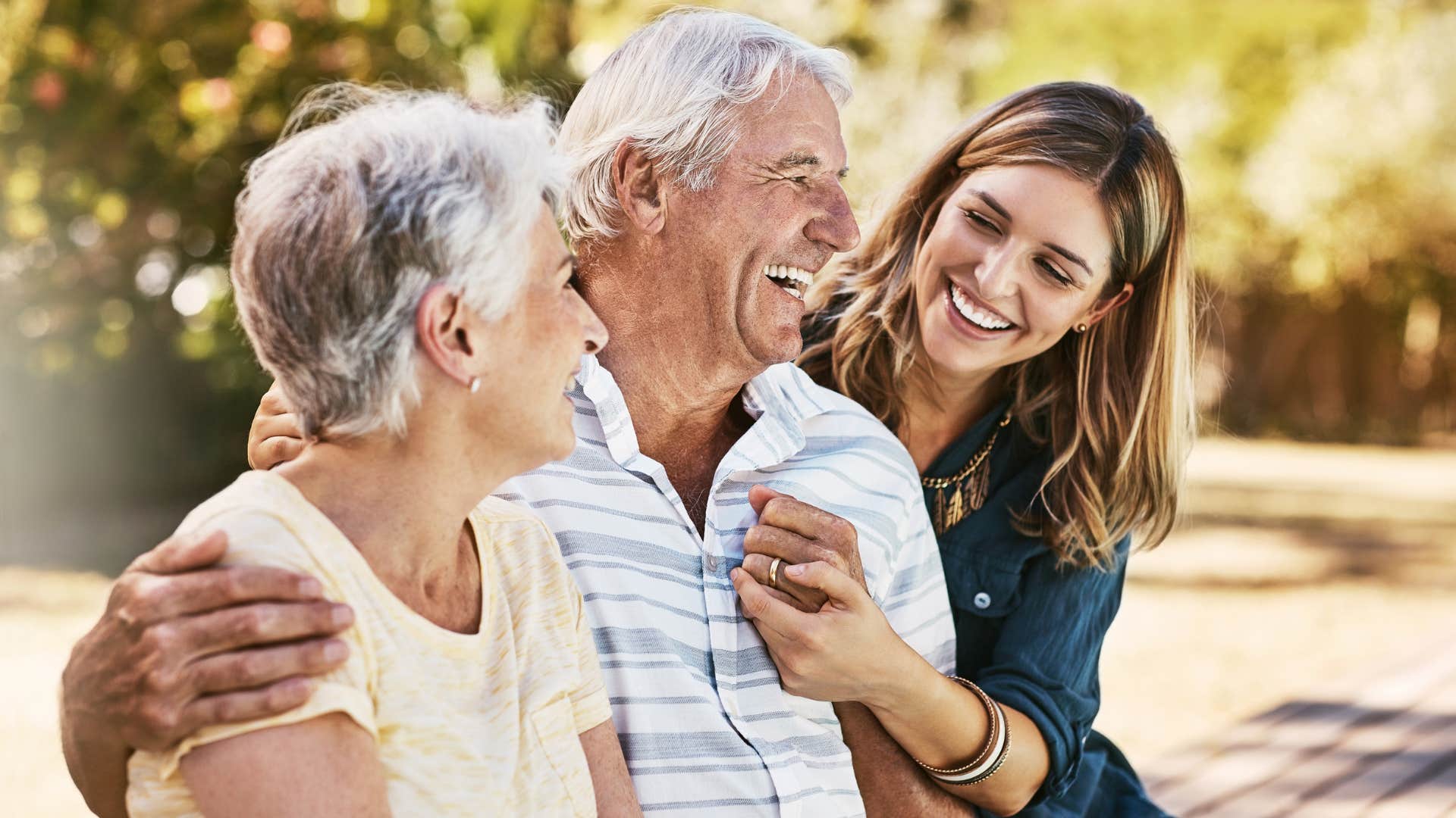 Adult daughter smiling and hugging her parents