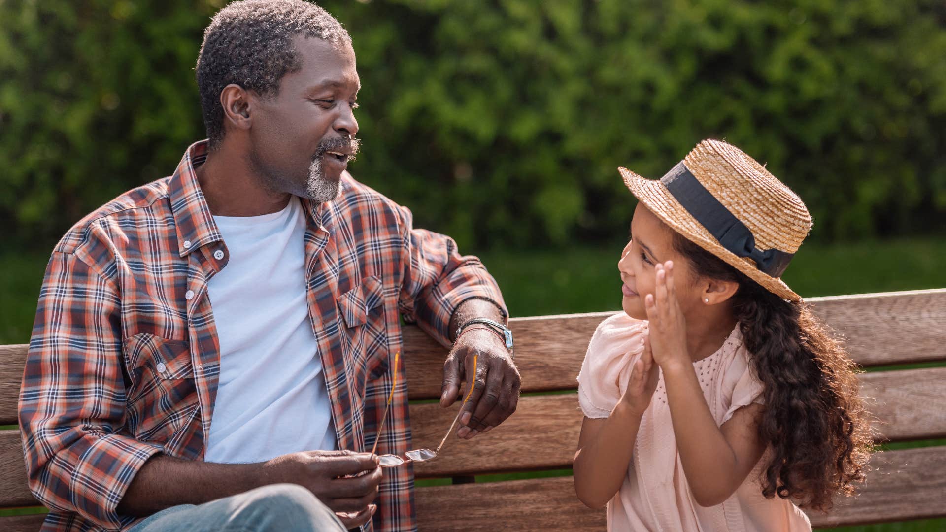 Grandfather smiling at his granddaughter on a park bench