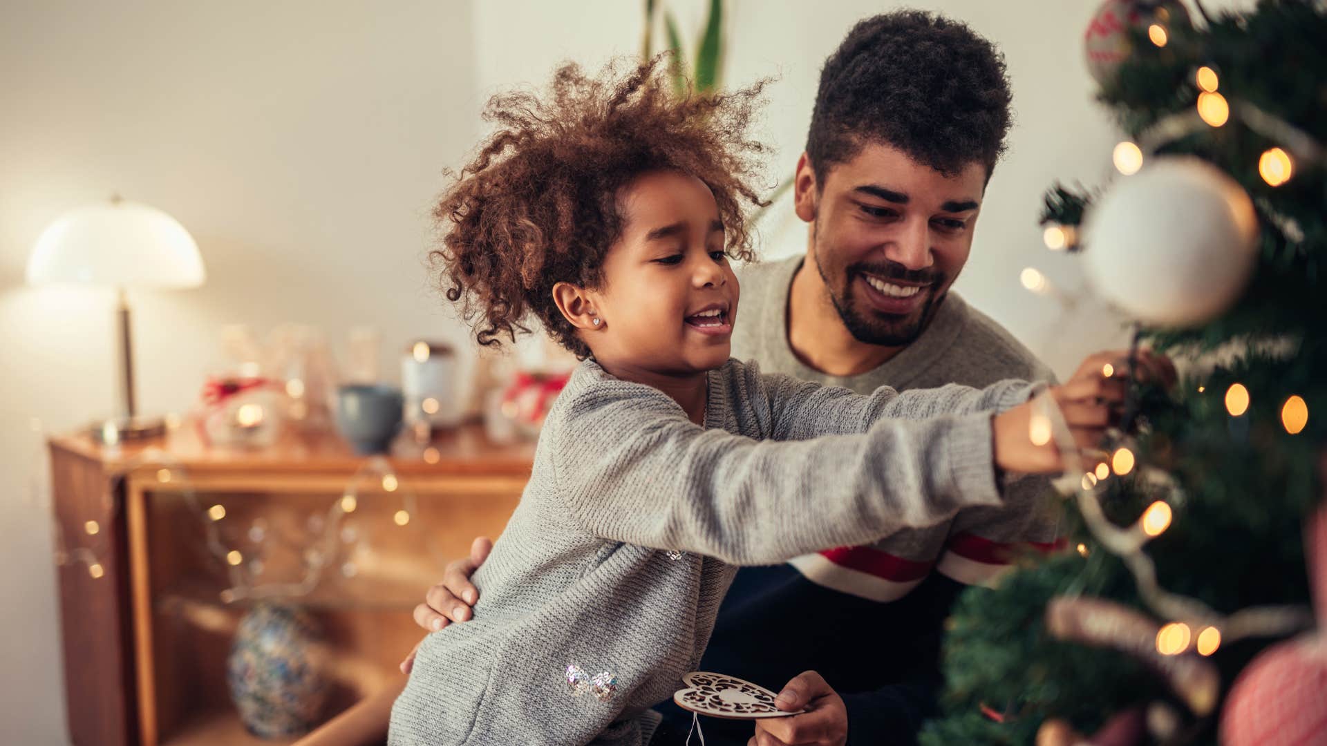 Man smiling and decorating a Christmas tree with his son