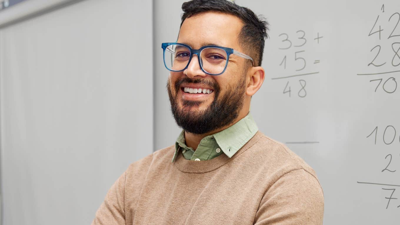 Young male teacher smiling in front of his classroom