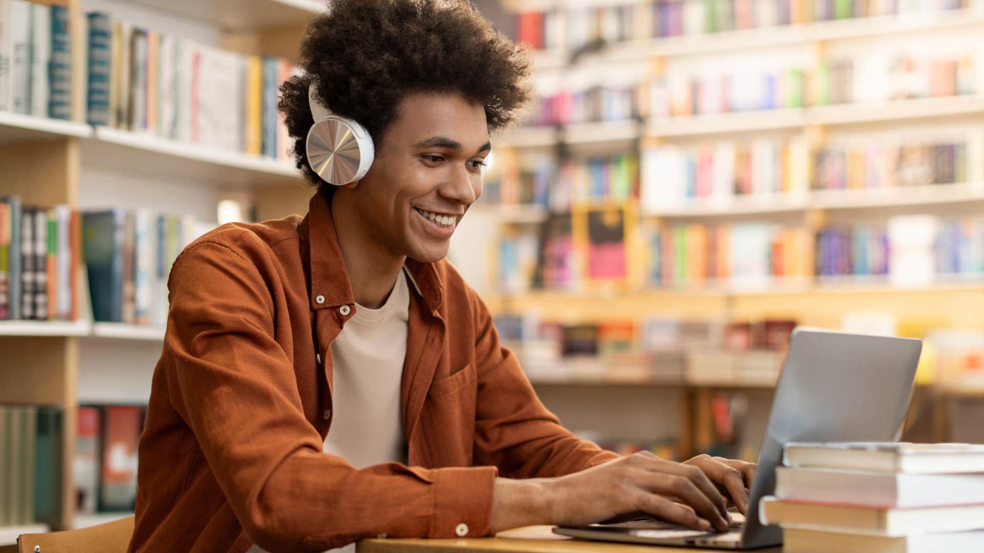 Gen Z student smiling and working on his laptop in the library