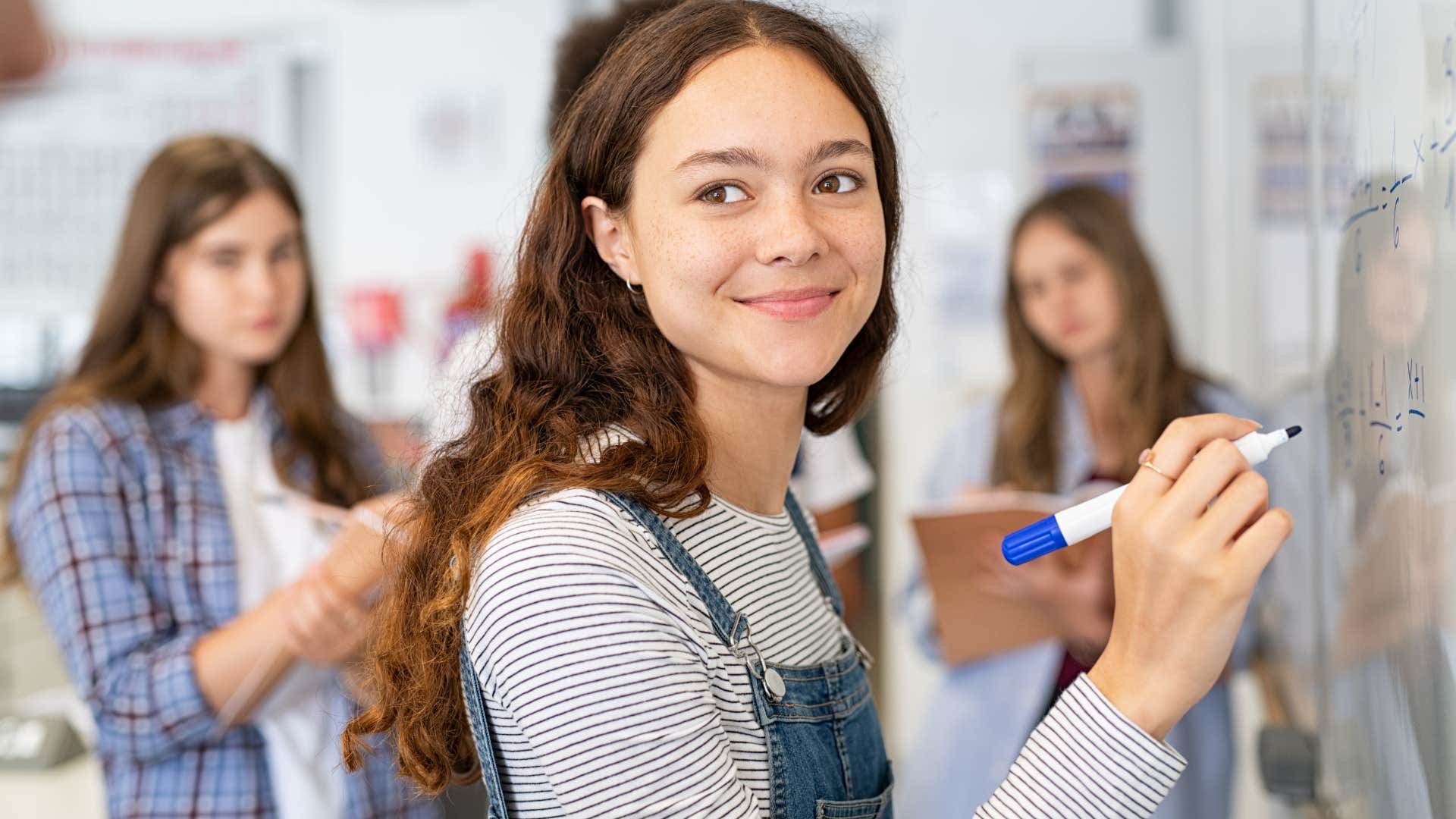 Gen Z girl smiling and writing on a whiteboard