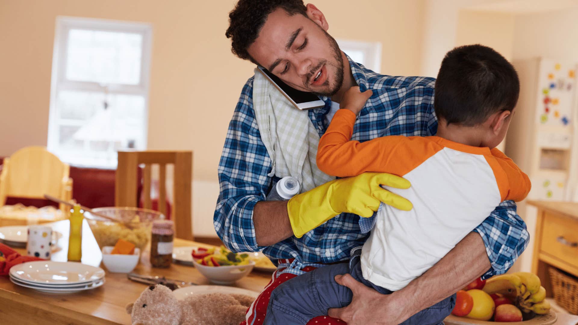 man doing chores while holding baby