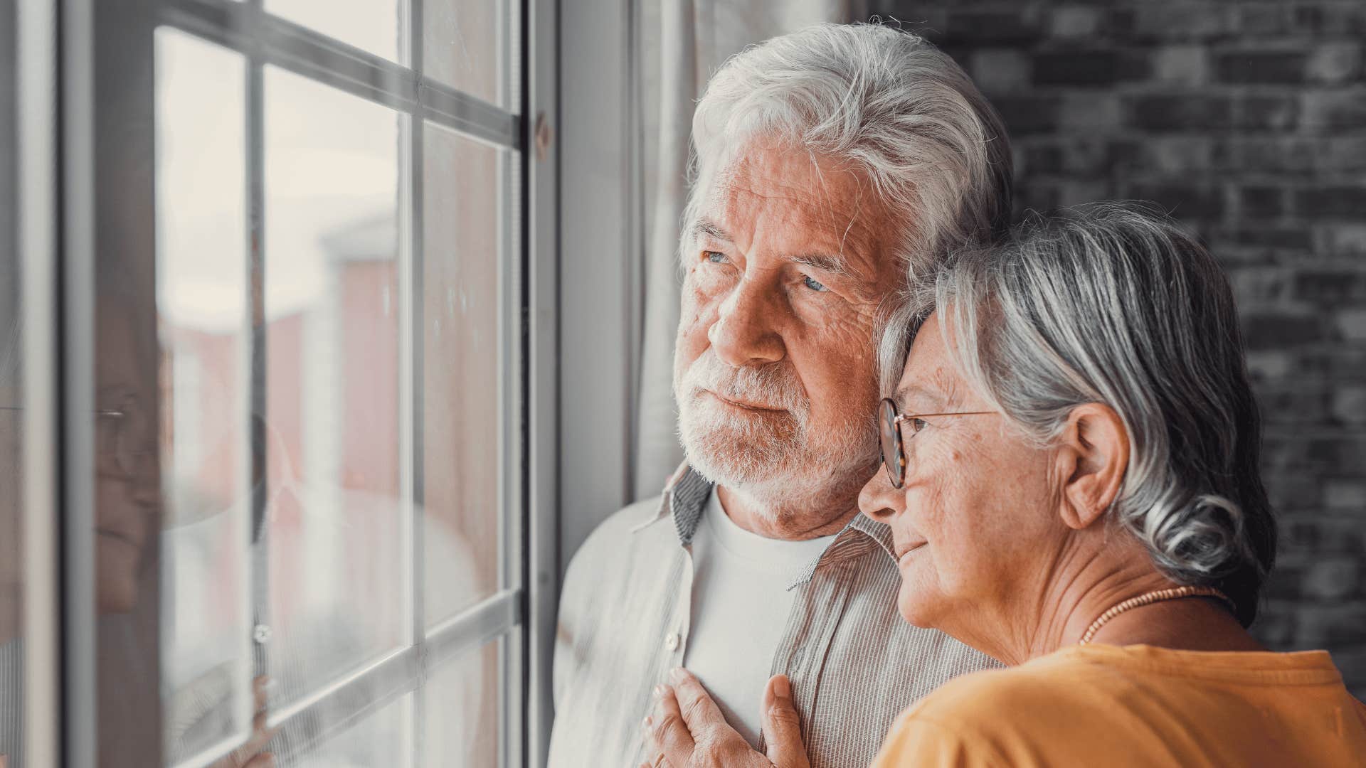 older man and woman looking out window