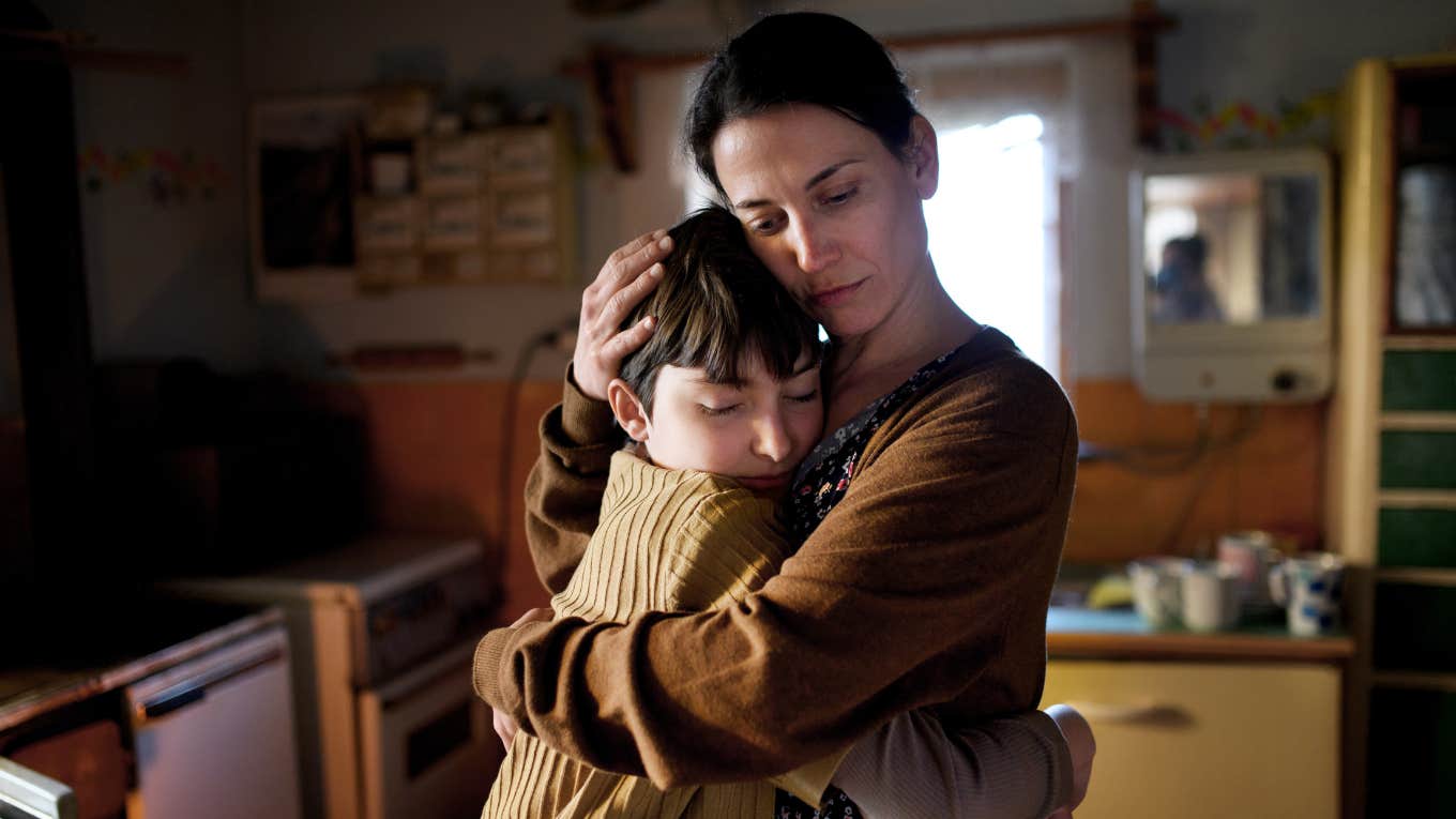 Portrait of sad mother hugging small daughter indoors at home