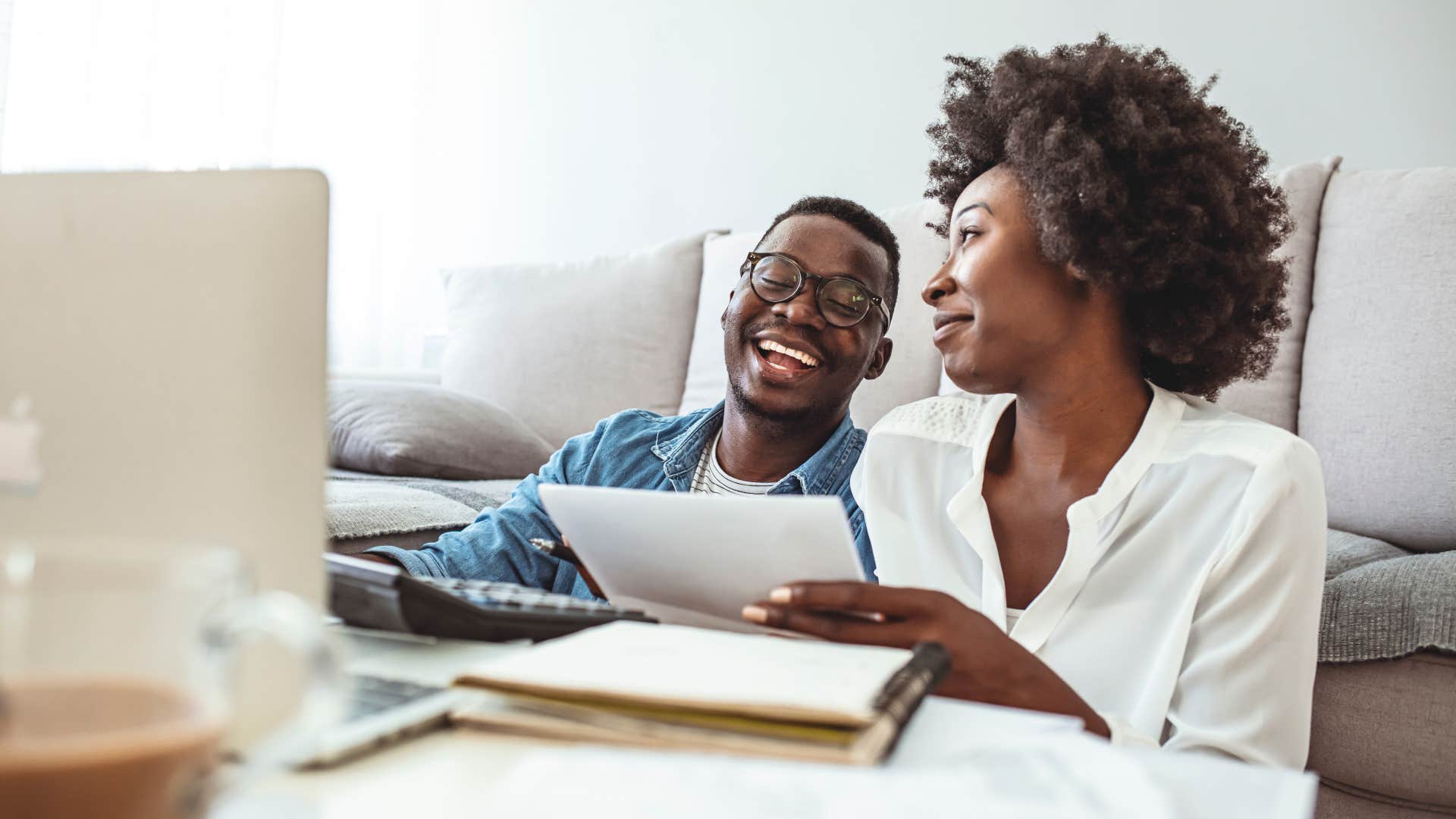 Couple smiling and doing bills together at a table