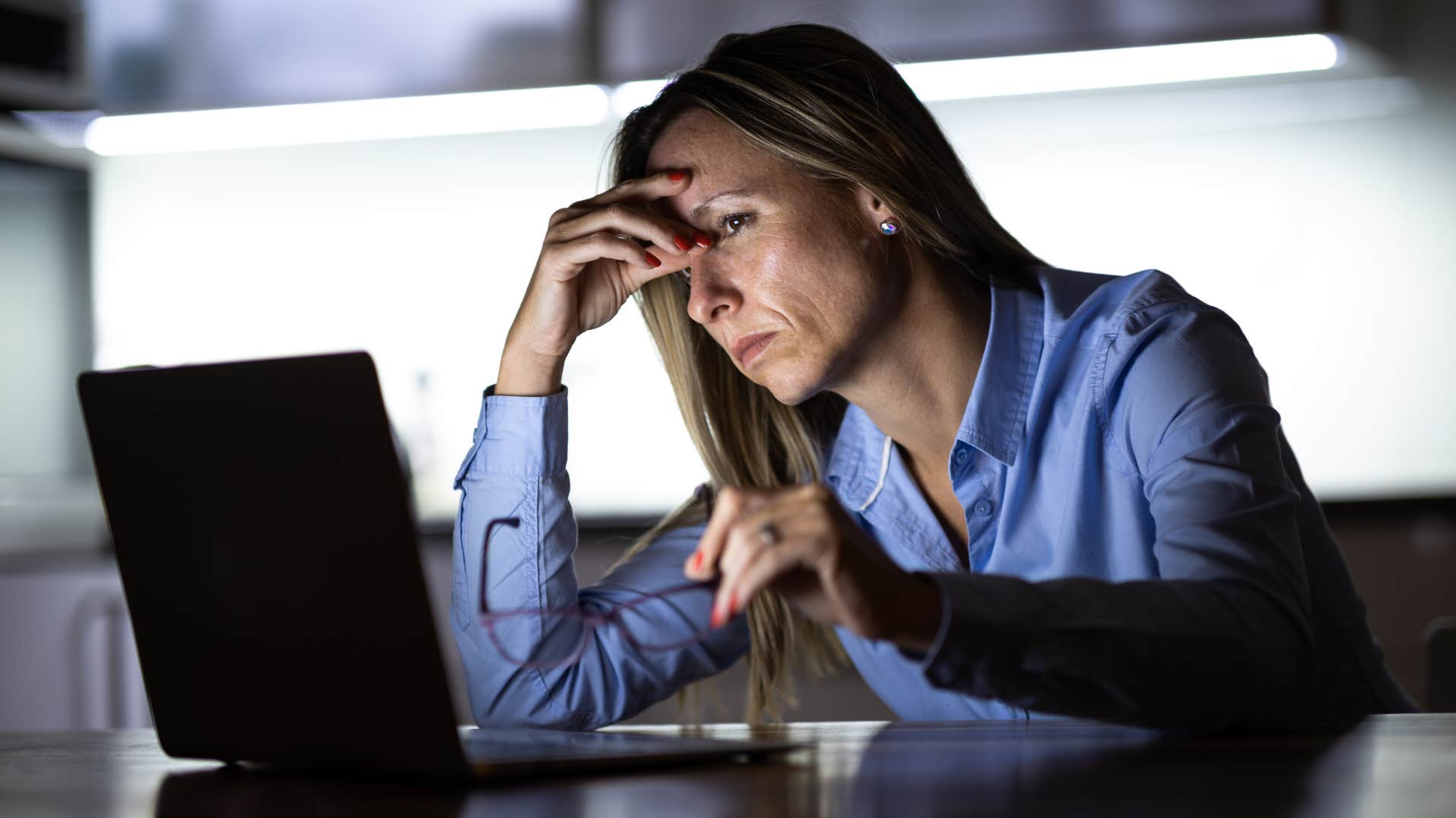 Woman working on her laptop in the dark. 