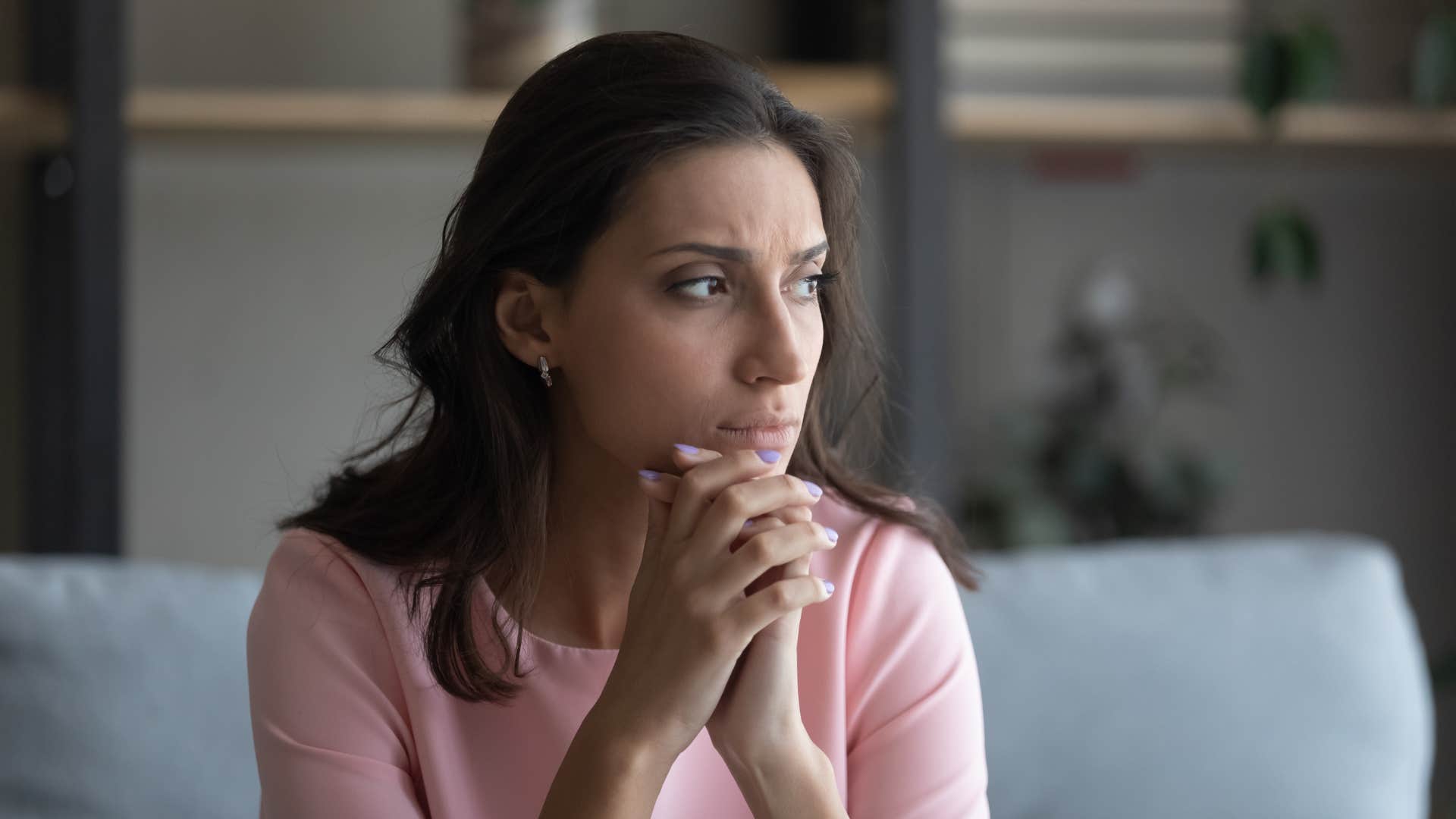 Anxious woman holding her hands up to her face.