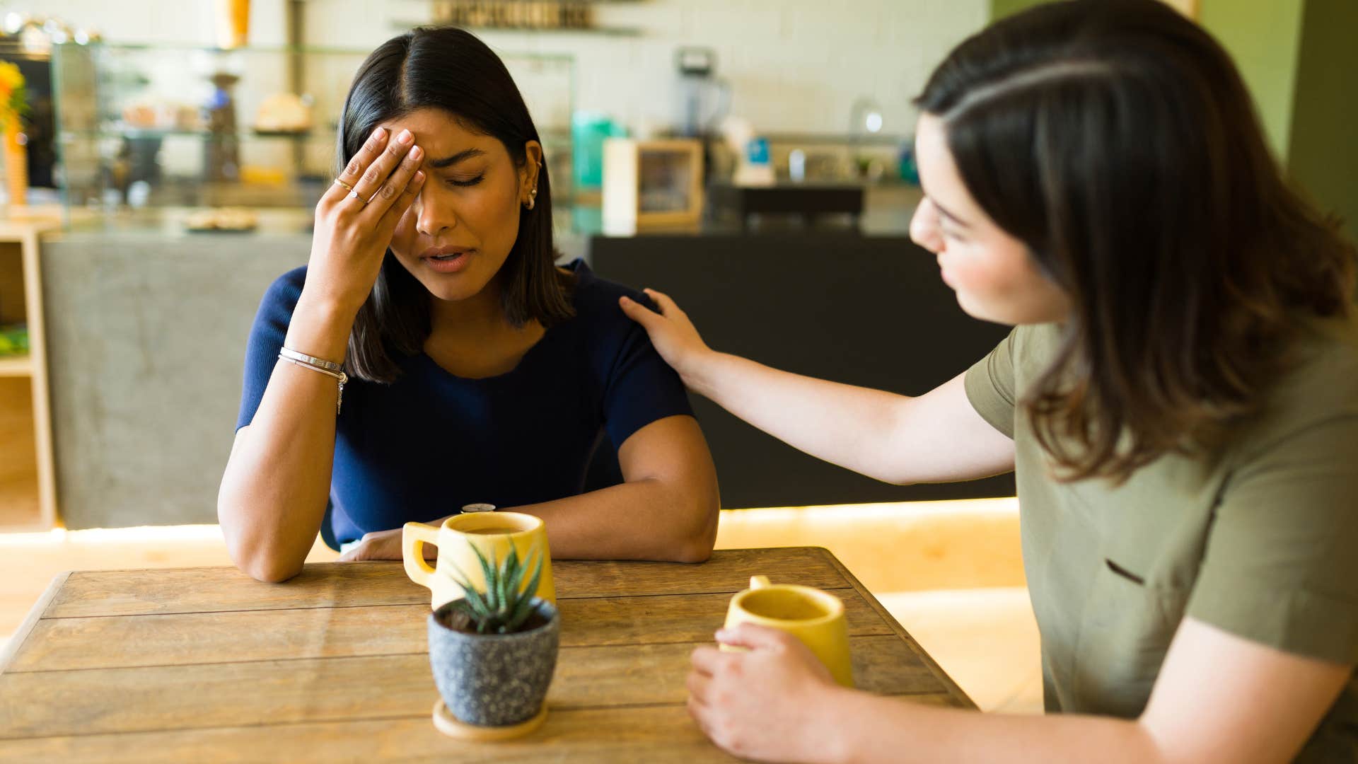 Woman comforting her upset friend at the table