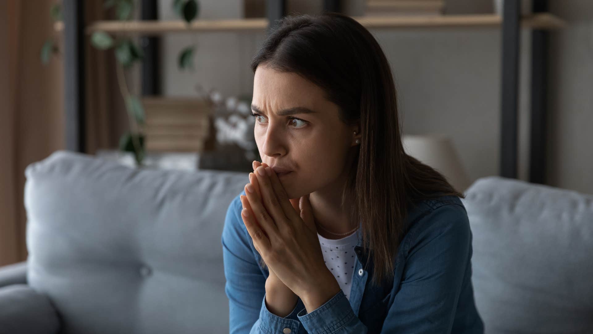 Woman looking stressed sitting on her couch