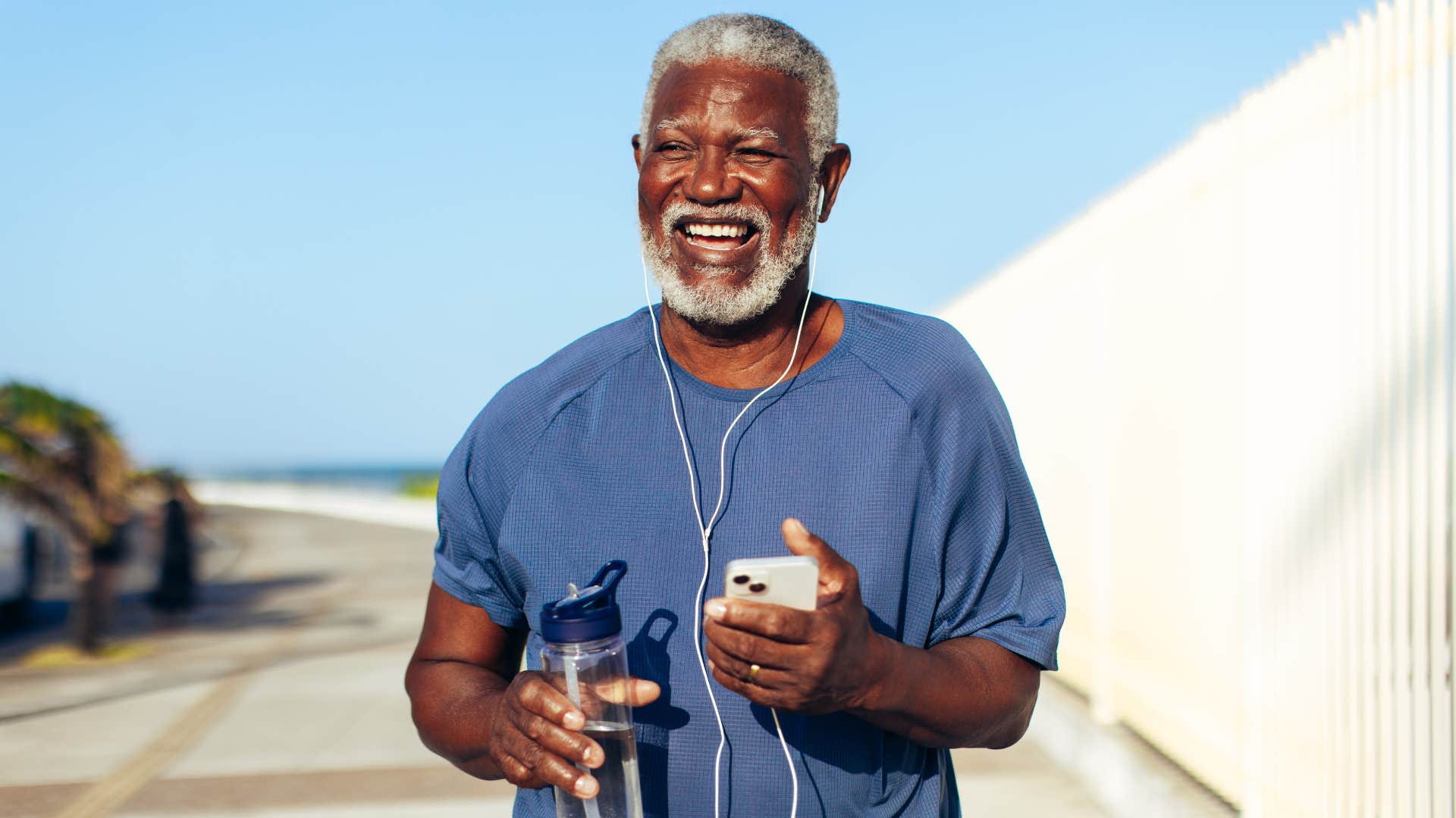 Older man walking outside with headphones on