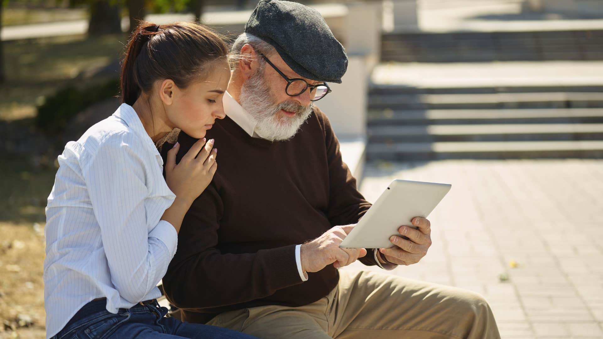 Woman sitting next to an older man looking at a tablet