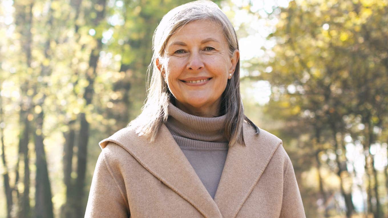 Older woman smiling at the camera outside in nature