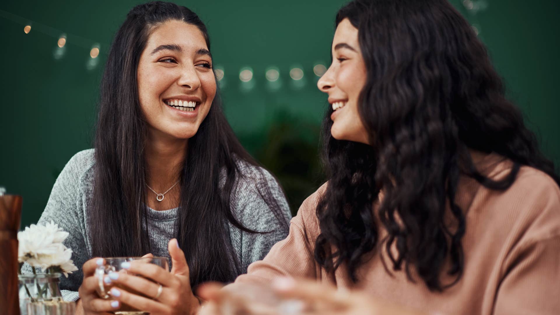 Two women smiling and drinking coffee together.