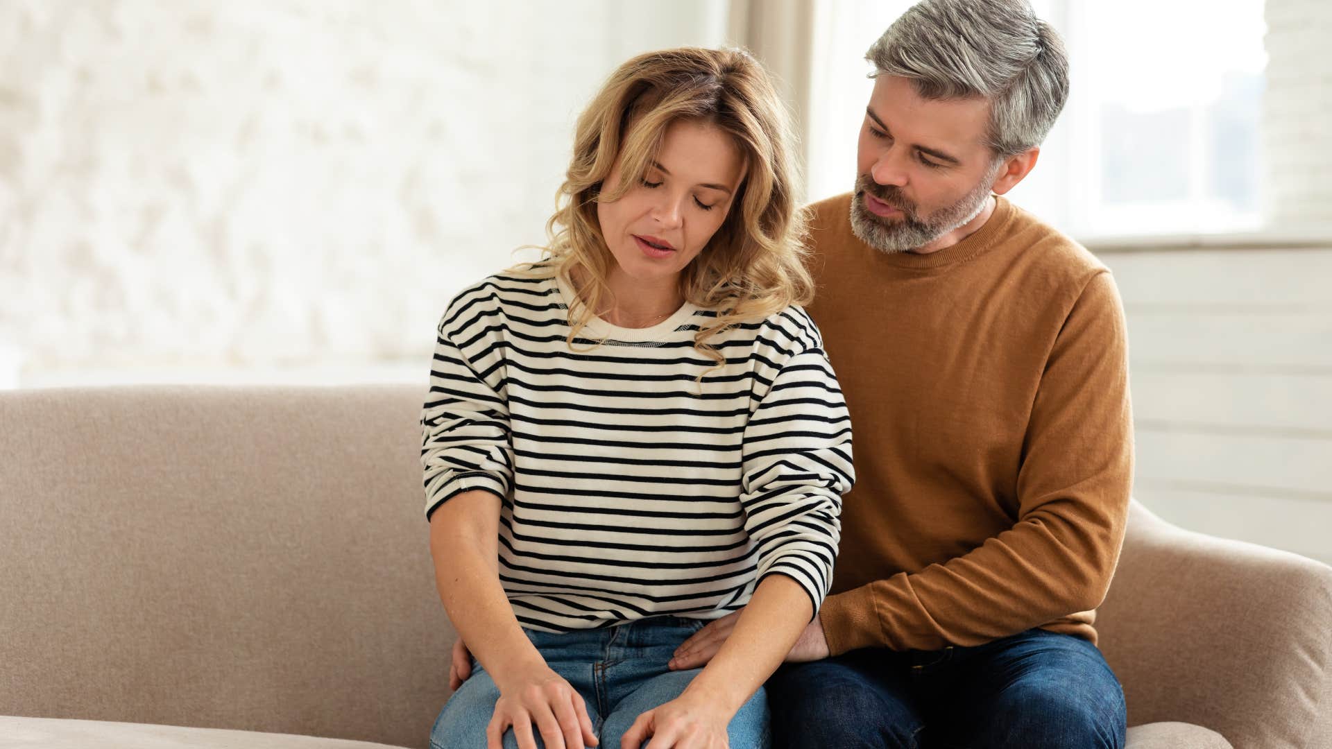 Man comforting his sad wife on the couch