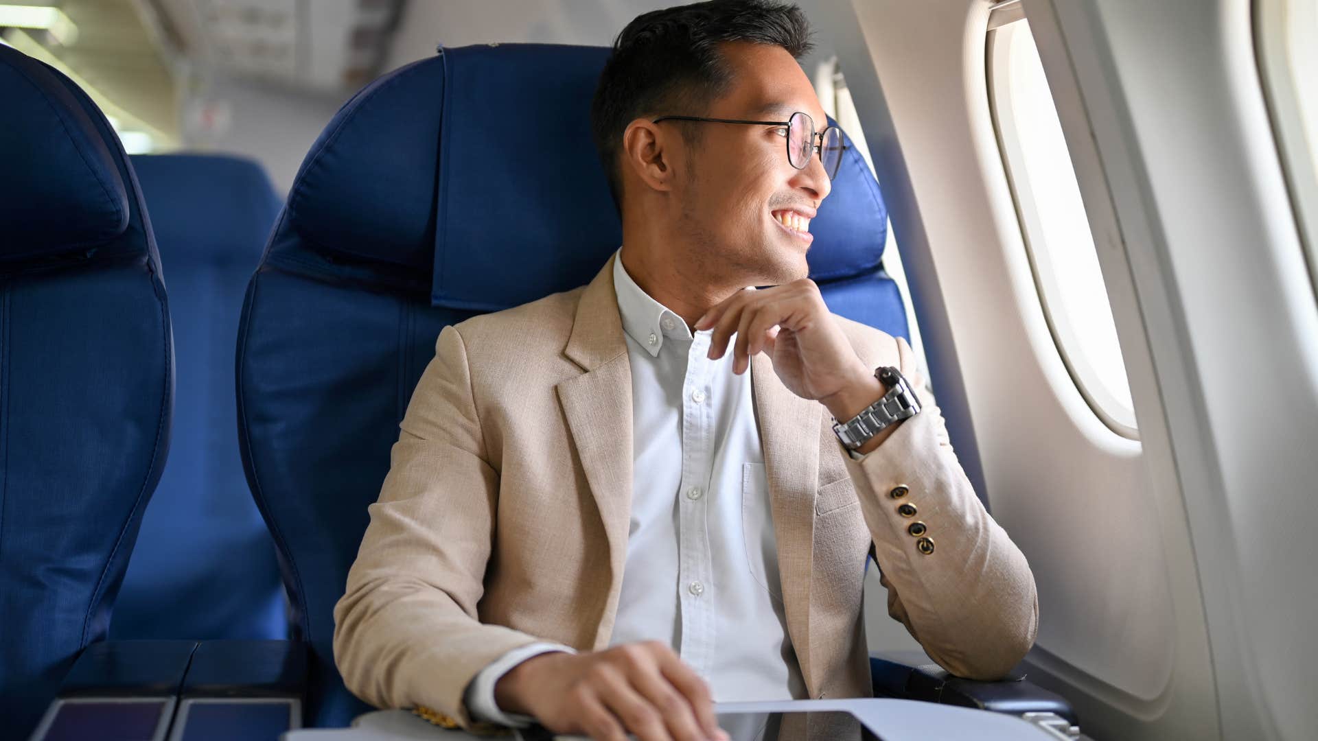 Man smiling and looking out of an airplane window