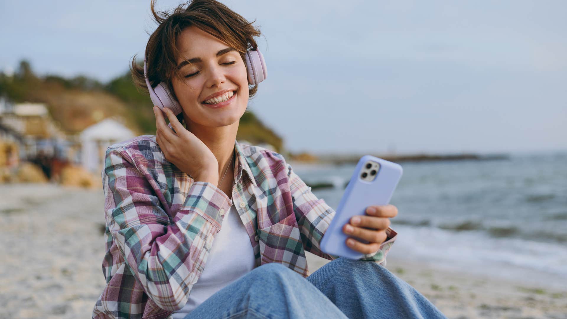 Woman smiling and listening to music on the beach