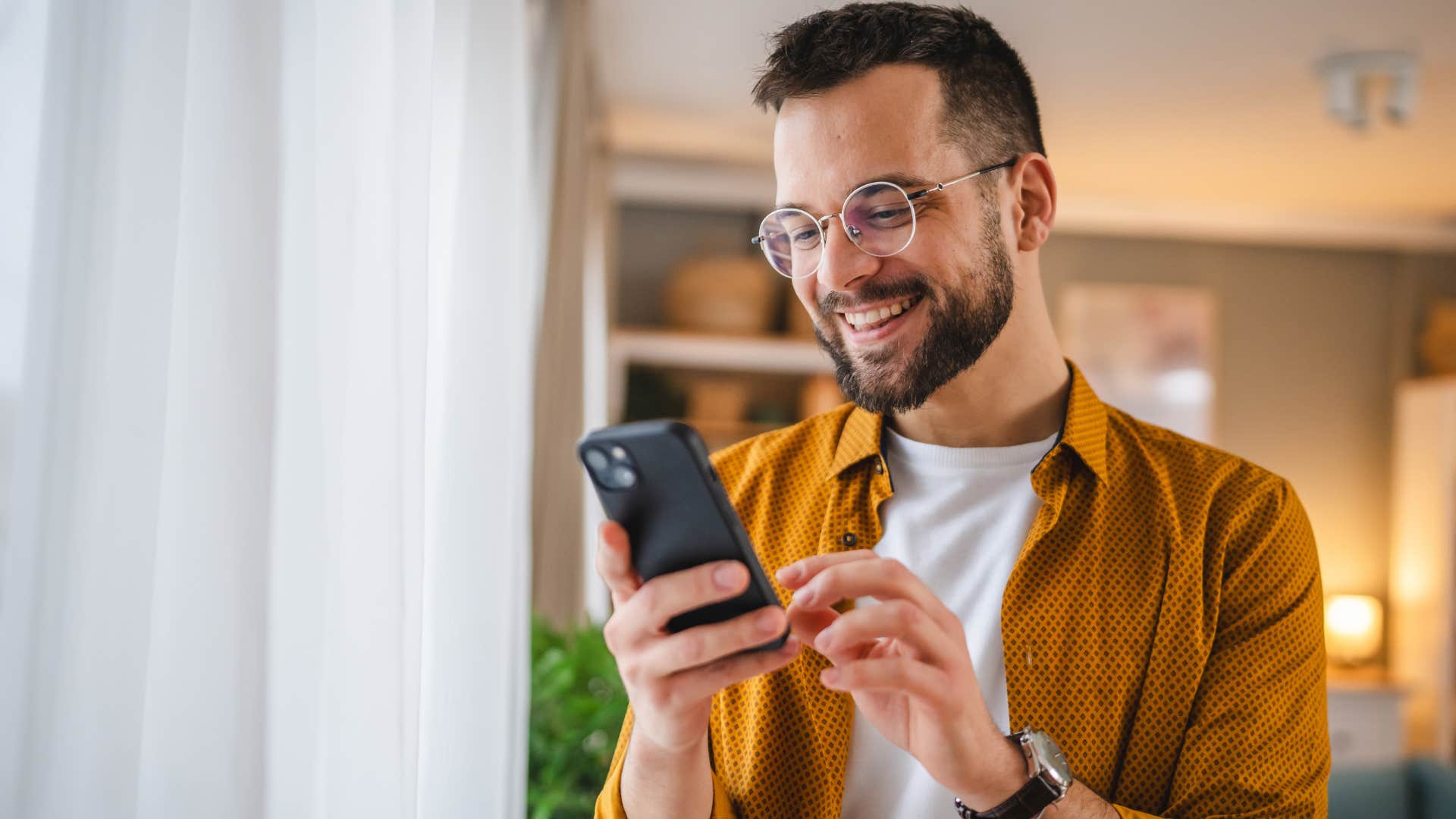 Man smiling and texting on his phone