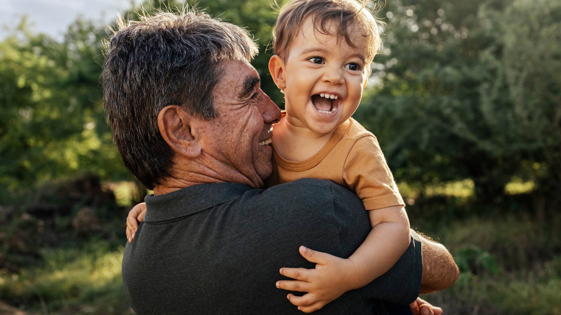 Man smiling and hugging his young son. 