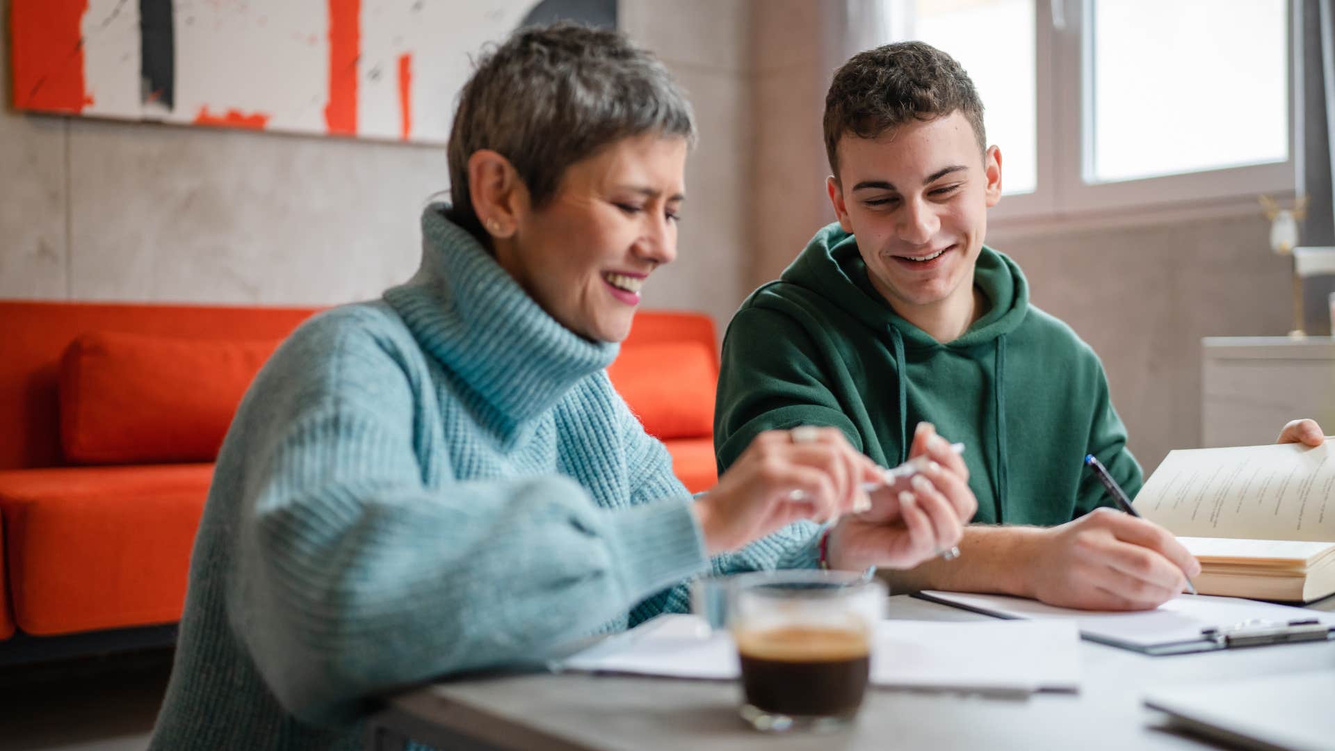 Woman smiling at the table with her teenage son.