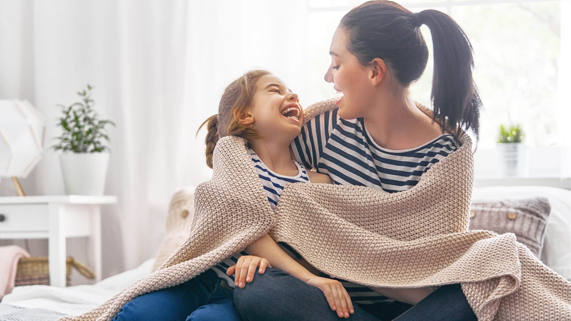 Mother smiling and hugging her young daughter.