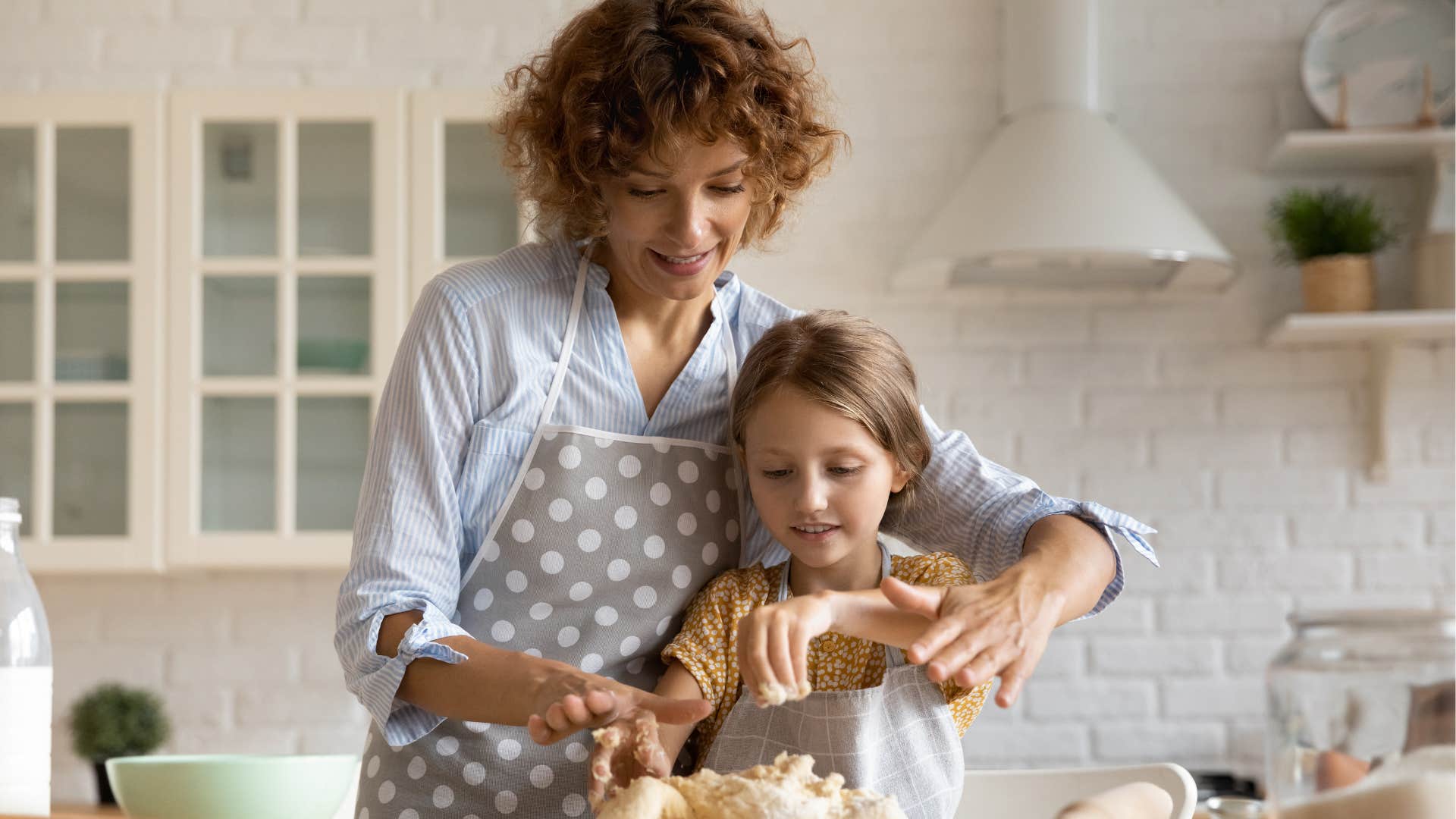 Woman smiling and cooking with her young daughter.