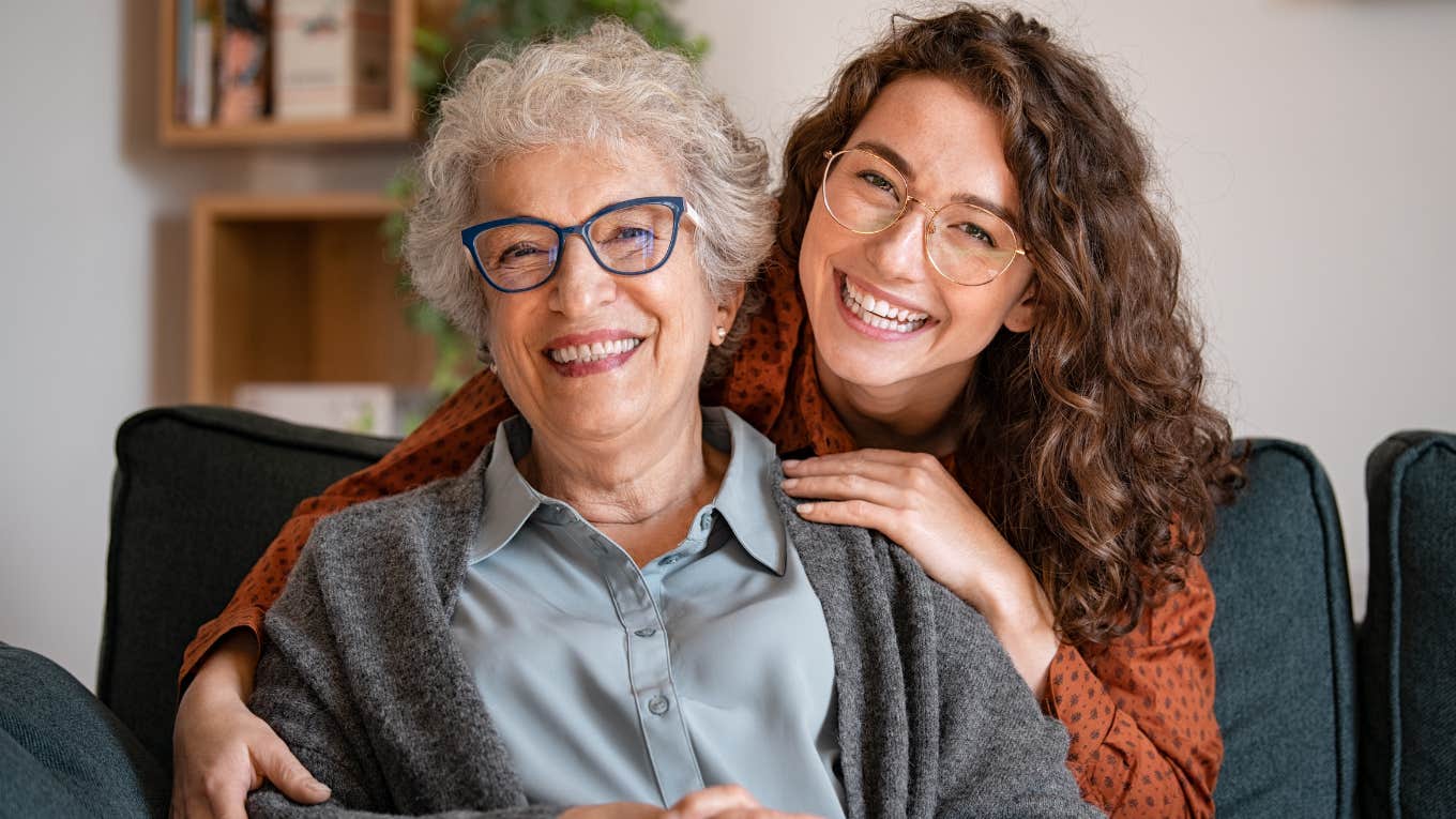 Young woman smiling and hugging her older mother on the couch