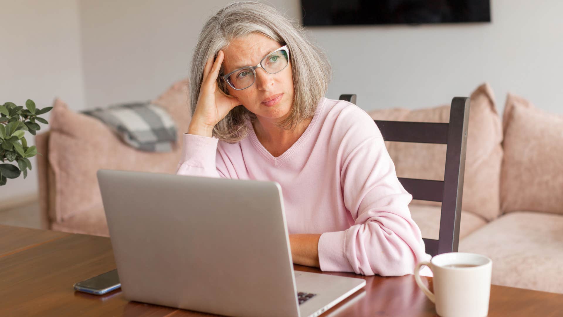 Woman looking upset sitting in front of her laptop.